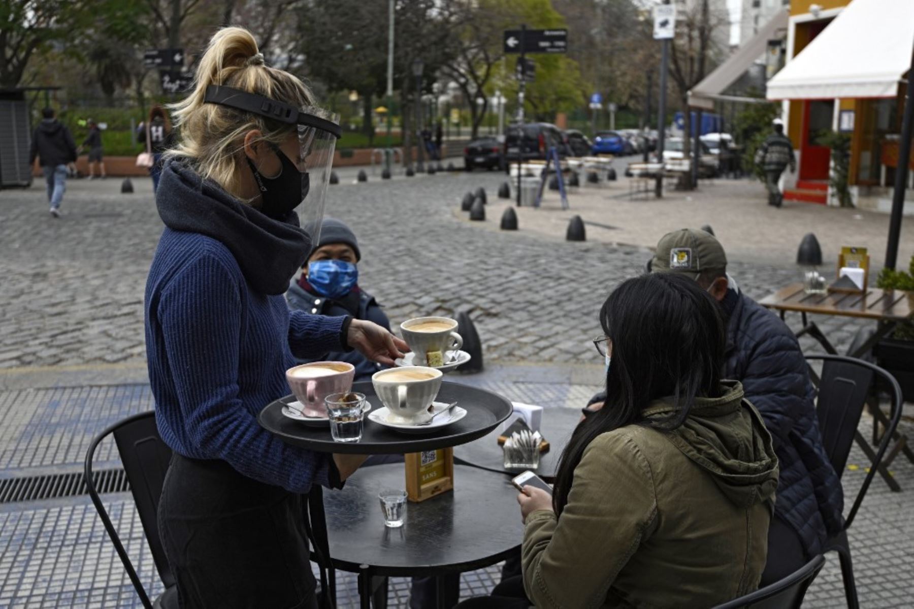 Una mesera sirve una mesa colocada en una acera en Buenos Aires, Argentina, en medio de la pandemia del covid-19. Foto: AFP
