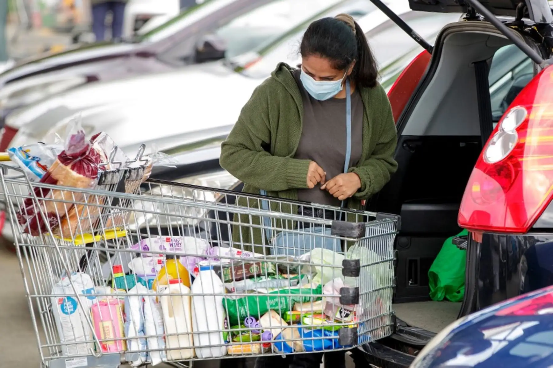 Un comprador vestido con una máscara facial empaca comestibles en el suburbio de Takapuna en Auckland. Foto: AFP