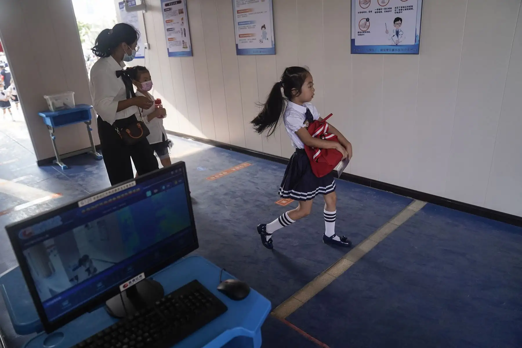 Una estudiante de primaria pasa junto a un escáner térmico cuando llega a la escuela el primer día del nuevo semestre en Wuhan, en la provincia central china de Hubei.
Foto: AFP