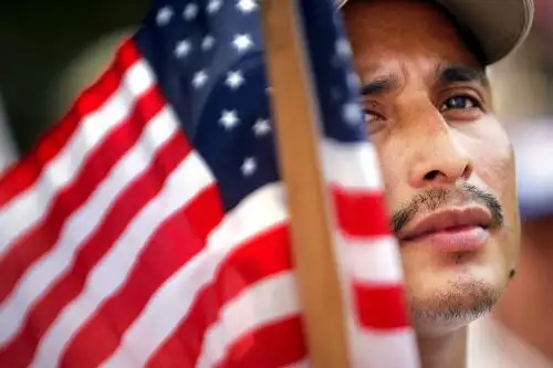 Orlando, un inmigrante de Guatemala, sostiene una bandera de Estados Unidos mientras se unía a cientos de otros inmigrantes durante una manifestación en el centro de Miami el 1 de mayo de 2007. Foto: AFP