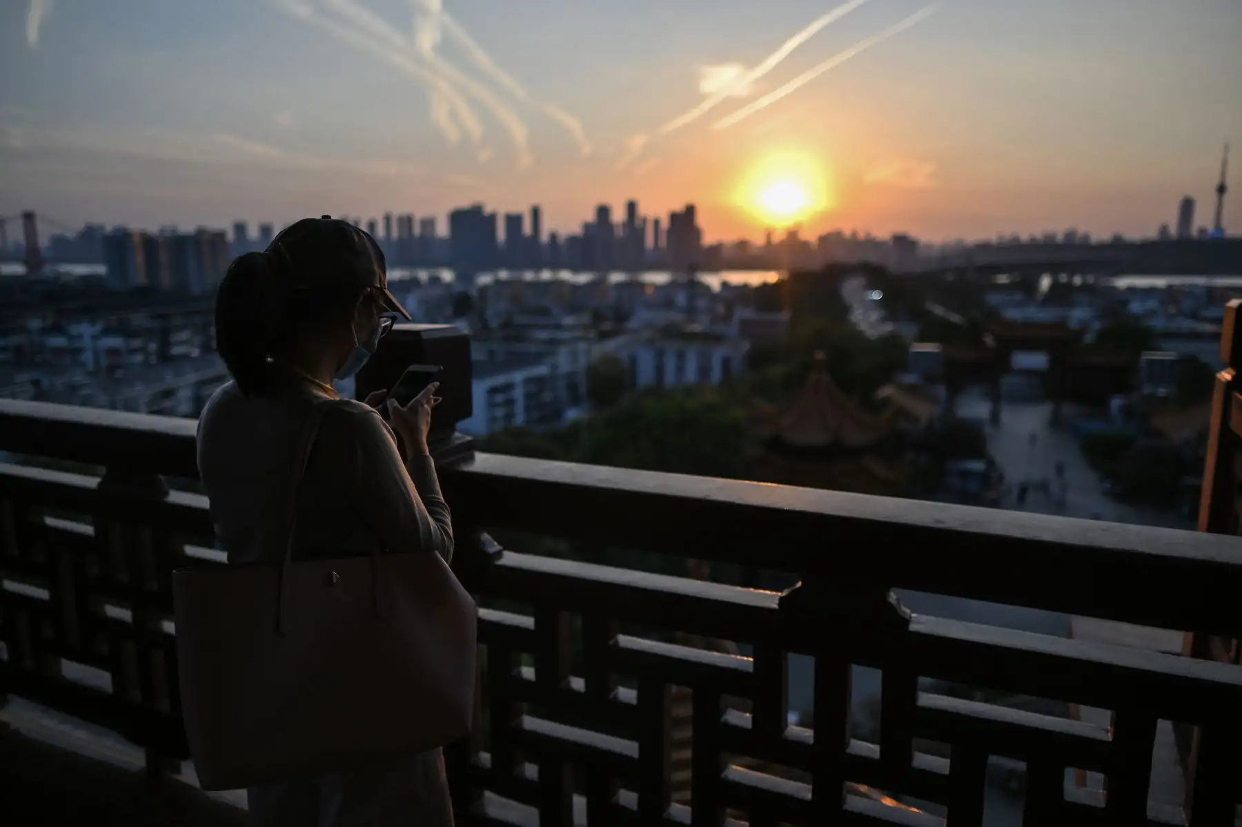 Una mujer con una máscara facial visita al atardecer la Torre de la Grulla Amarilla en Wuhan, provincia central de Hubei en China.
Foto: AFP