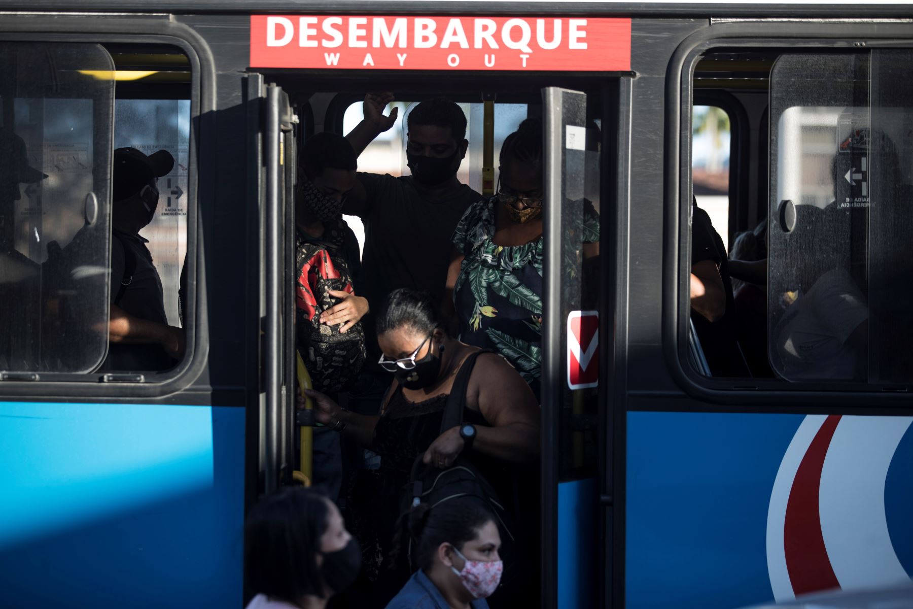 Pasajeros con mascarillas para prevenir la propagación del coronavirus descienden de un autobús en Río de Janeiro.
Foto: AFP