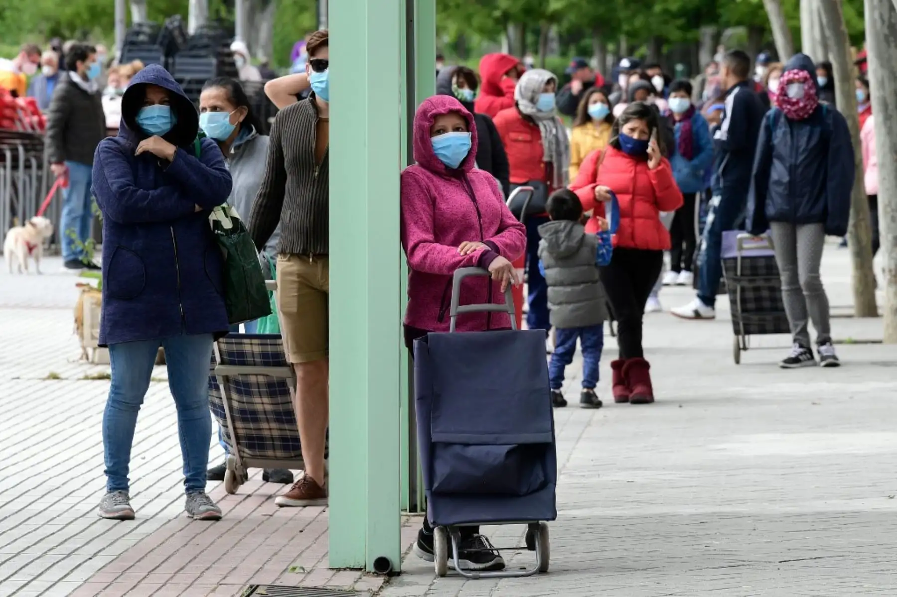 La gente hace cola para obtener una ración de comida gratuita del banco de alimentos de la Asociación de Vecinos de Aluche en Madrid. Foto: AFP