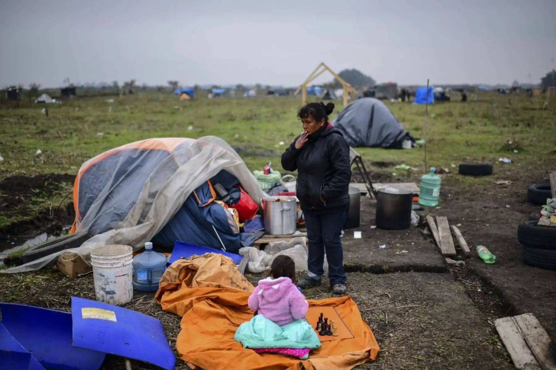 Una mujer y una niña son vistas junto a una carpa instalada en un terreno ocupado por personas sin hogar en las afueras de Guernica, en la provincia de Buenos Aires. Foto: AFP