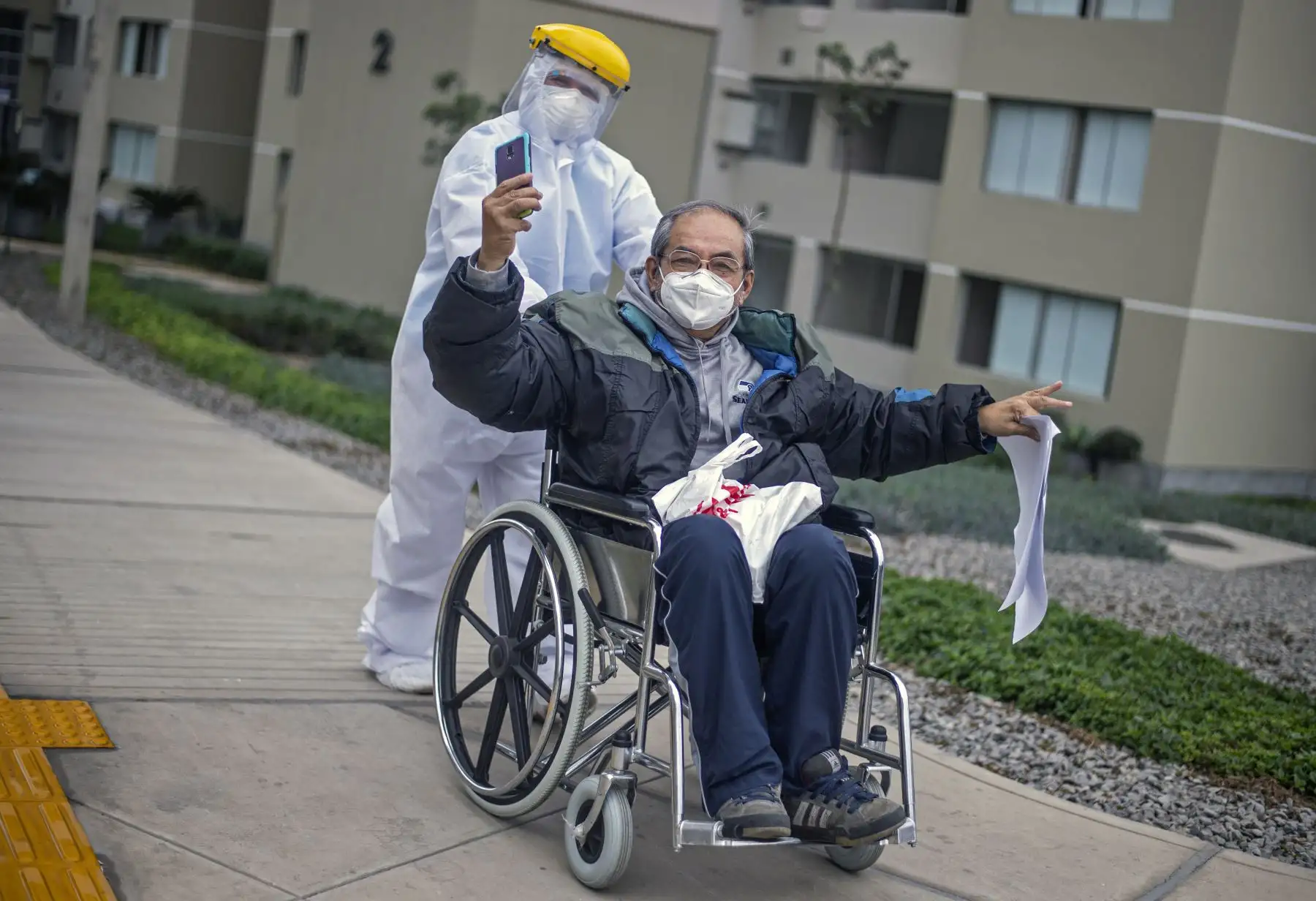 César Sayan, quien se recuperó del covid-19, gesticula alegría mientras un trabajador de salud lo empuja en una silla de ruedas luego de ser dado de alta de la Villa Panamericana, un complejo habitacional reconvertido en hospital, en el distrito de Villa El Salvador, en la periferia sur de Lima.Más de 10,000 personas se han recuperado de covid-19 en Perú, que registra más de 660,000 casos y más de 29,000 muertes. Foto: AFP