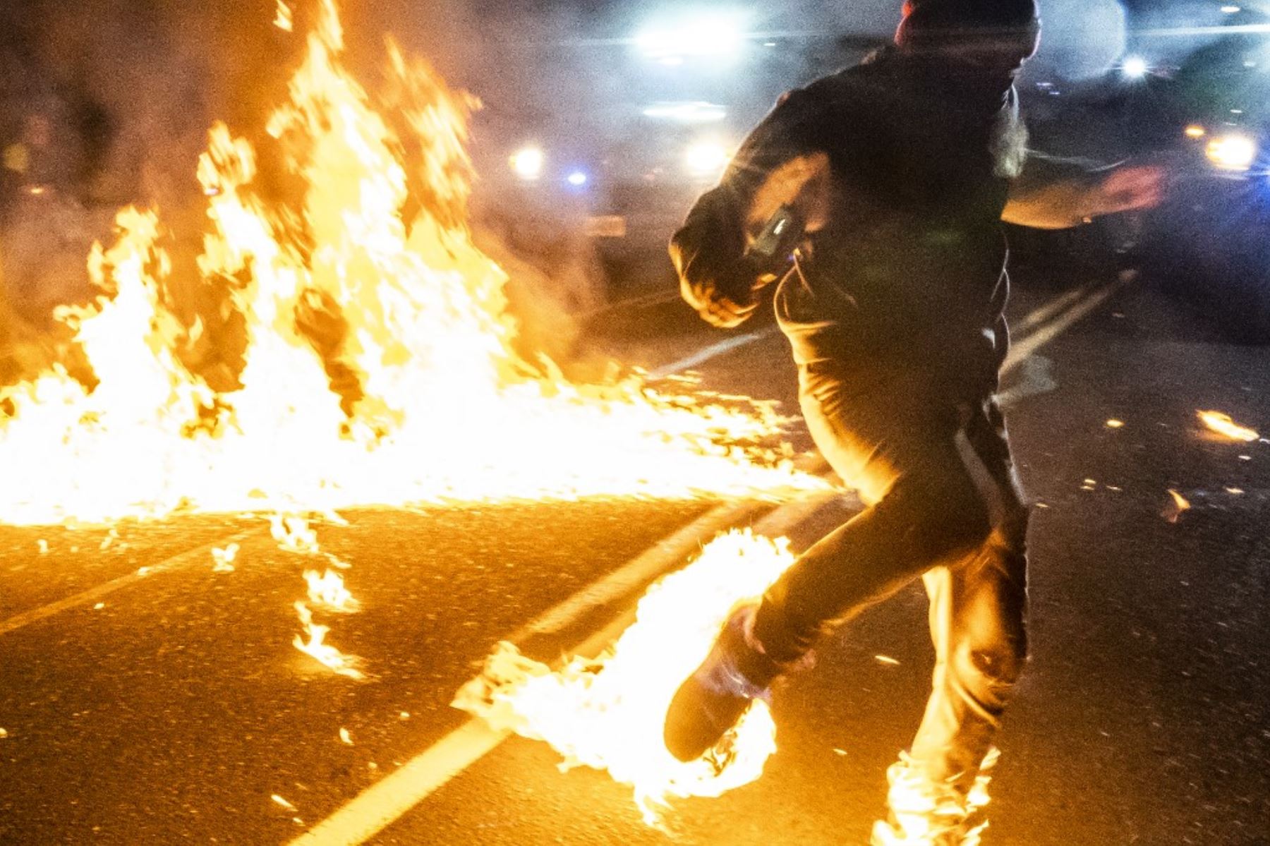 Un manifestante, cuyos pies se incendiaron después de que un cóctel molotov explotó sobre él, corre hacia un médico durante una protesta contra la brutalidad policial y la injusticia racial en Portland, Oregon. Foto: AFP