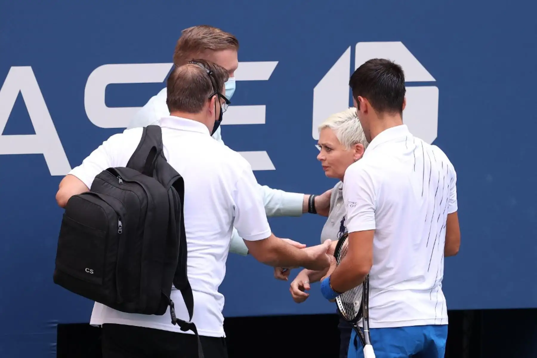 El tenista serbio, Novak Djokovic, atiende a una juez de línea que fue golpeada, sin intención, con la pelota por el propio jugador durante su partido de cuarta ronda de hombres individuales contra Pablo Carreño Busta de España en el séptimo día del Abierto de Estados Unidos 2020. Por esta acción, el jugador fue descalificado del torneo. Foto: AFP