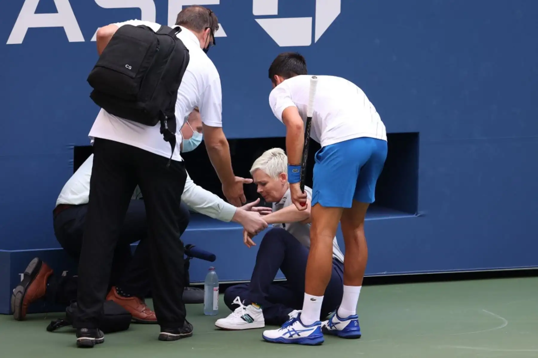 El tenista serbio, Novak Djokovic, atiende a una juez de línea que fue golpeada, sin intención, con la pelota por el propio jugador durante su partido de cuarta ronda de hombres individuales contra Pablo Carreño Busta de España en el séptimo día del Abierto de Estados Unidos 2020. Por esta acción, el jugador fue descalificado del torneo. Foto: AFP