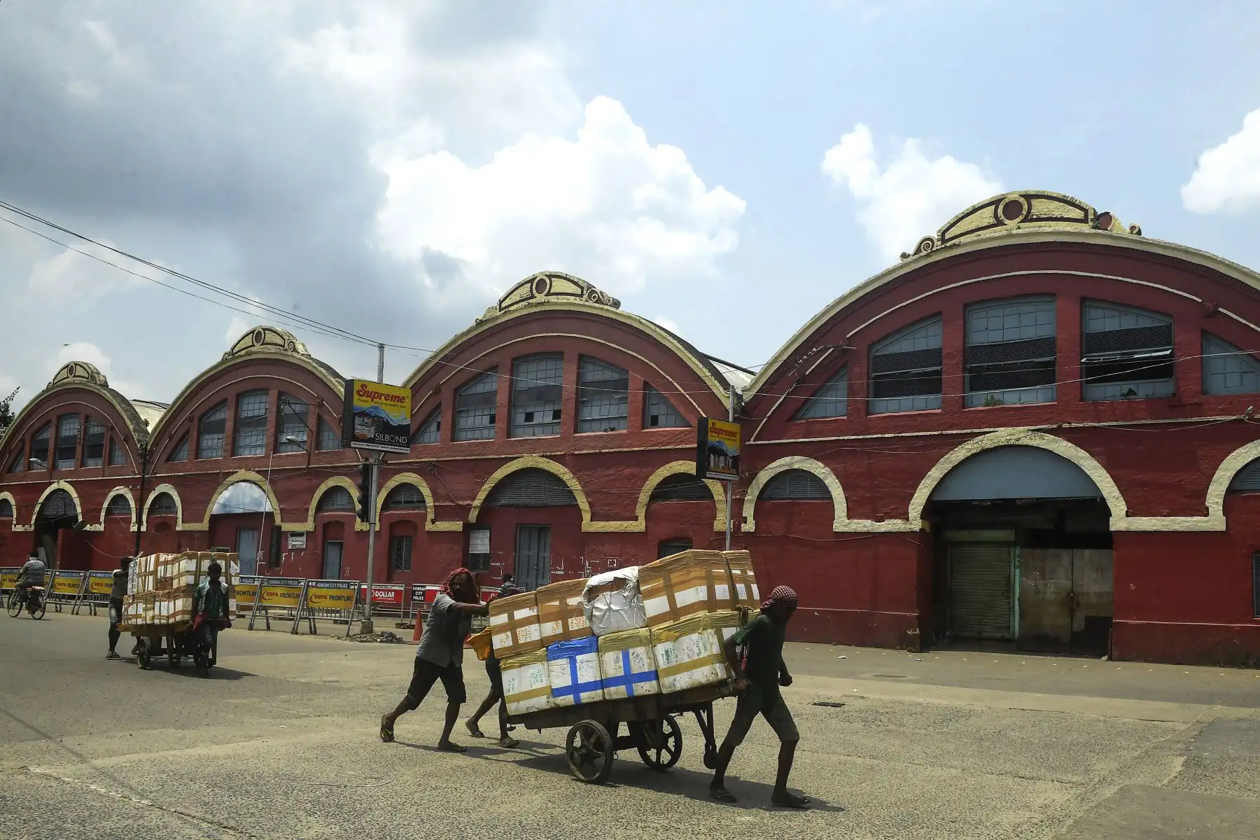 Trabajadores empujan un cargamento en la estación de tren de Howrah durante un día de cierre impuesto por el estado como medida preventiva ante el aumento en los casos de coronavirus. Foto: AFP