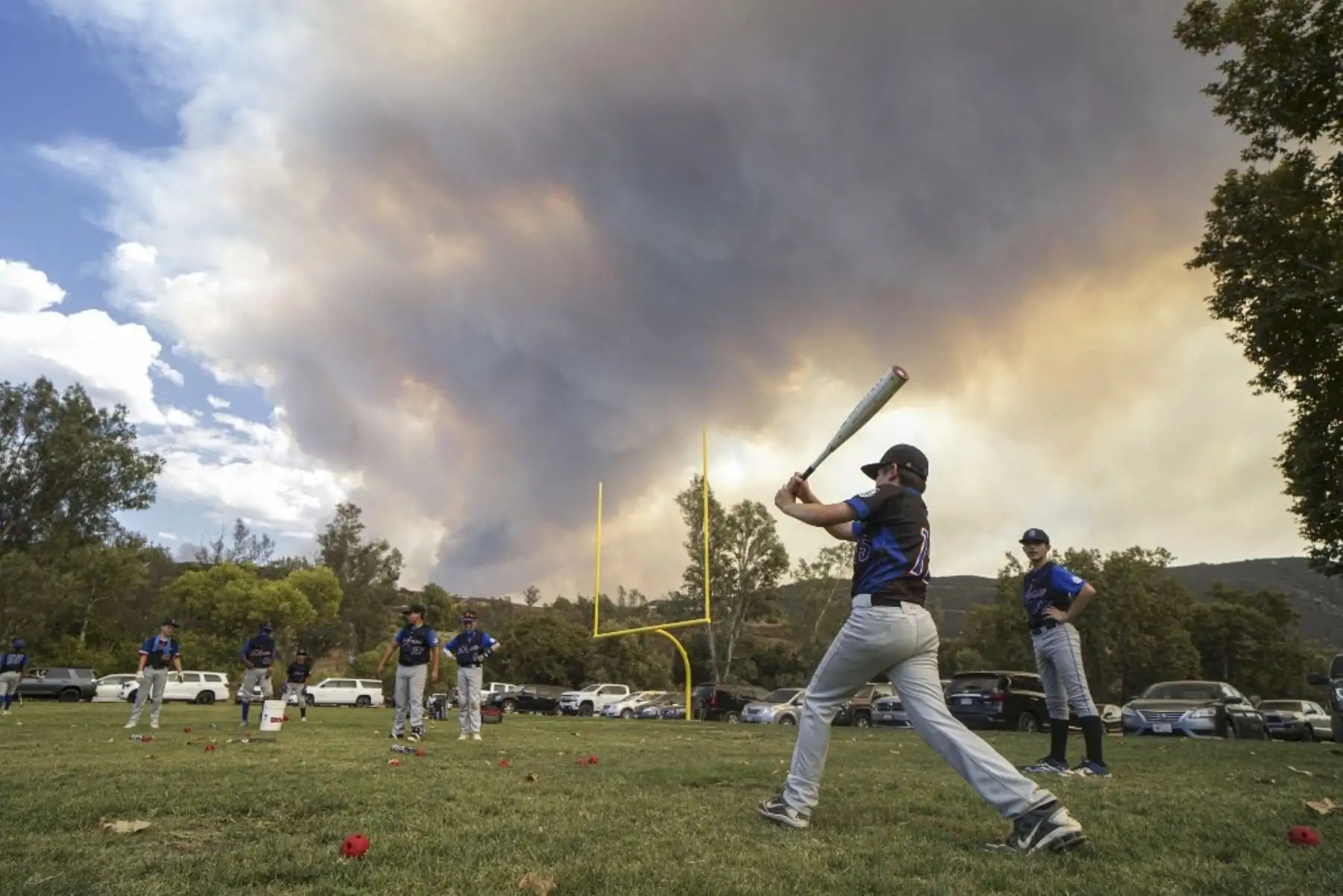 Jugadores de baseball juegan cerca del incendio en el condado de Madera, California. Foto: AFP
