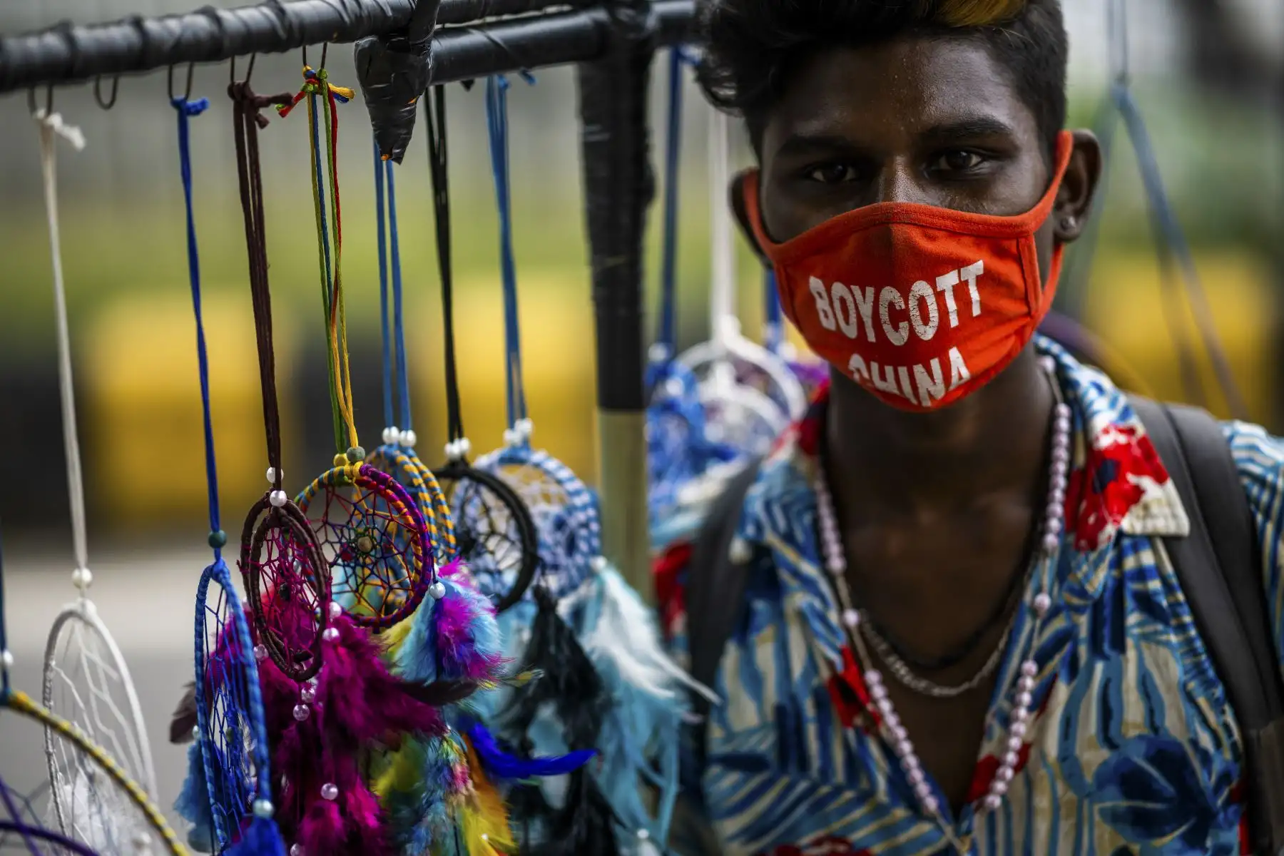 Un proveedor que usa una mascarilla como medida preventiva ante el coronavirus busca compradores para sus artículos decorativos, en Nueva Delhi. Foto: AFP