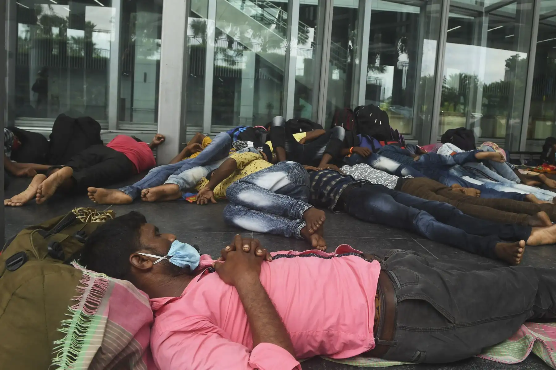 Los trabajadores migrantes descansan fuera de la sala de salidas del Aeropuerto Internacional Netaji Subhash Chandra Bose, luego que sus vuelos fueran cancelados. Foto: AFP