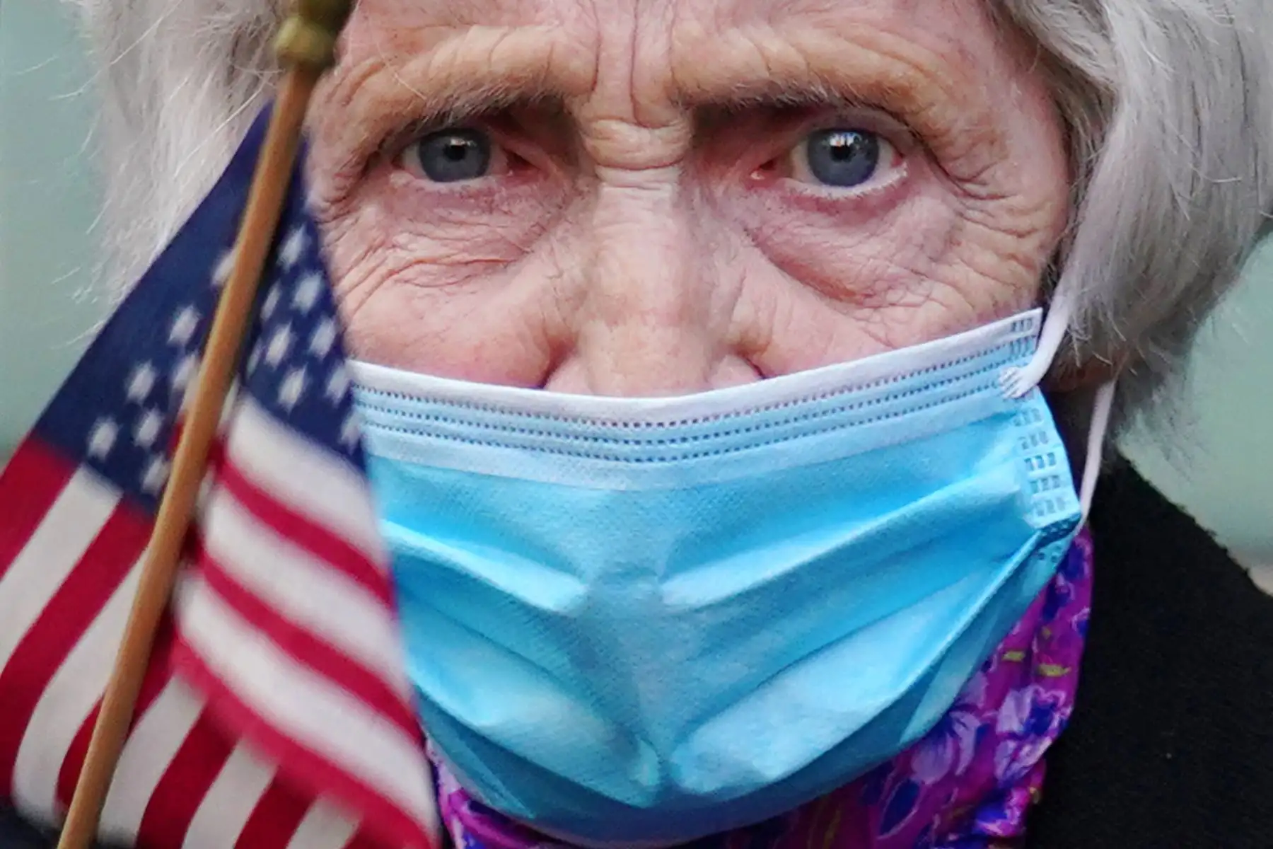 Una mujer con una máscara protectora sostiene una bandera estadounidense mientras la gente muestra gratitud a los trabajadores médicos y de primera línea en el Hospital Lenox Hill durante la pandemia de coronavirus. Foto: AFP