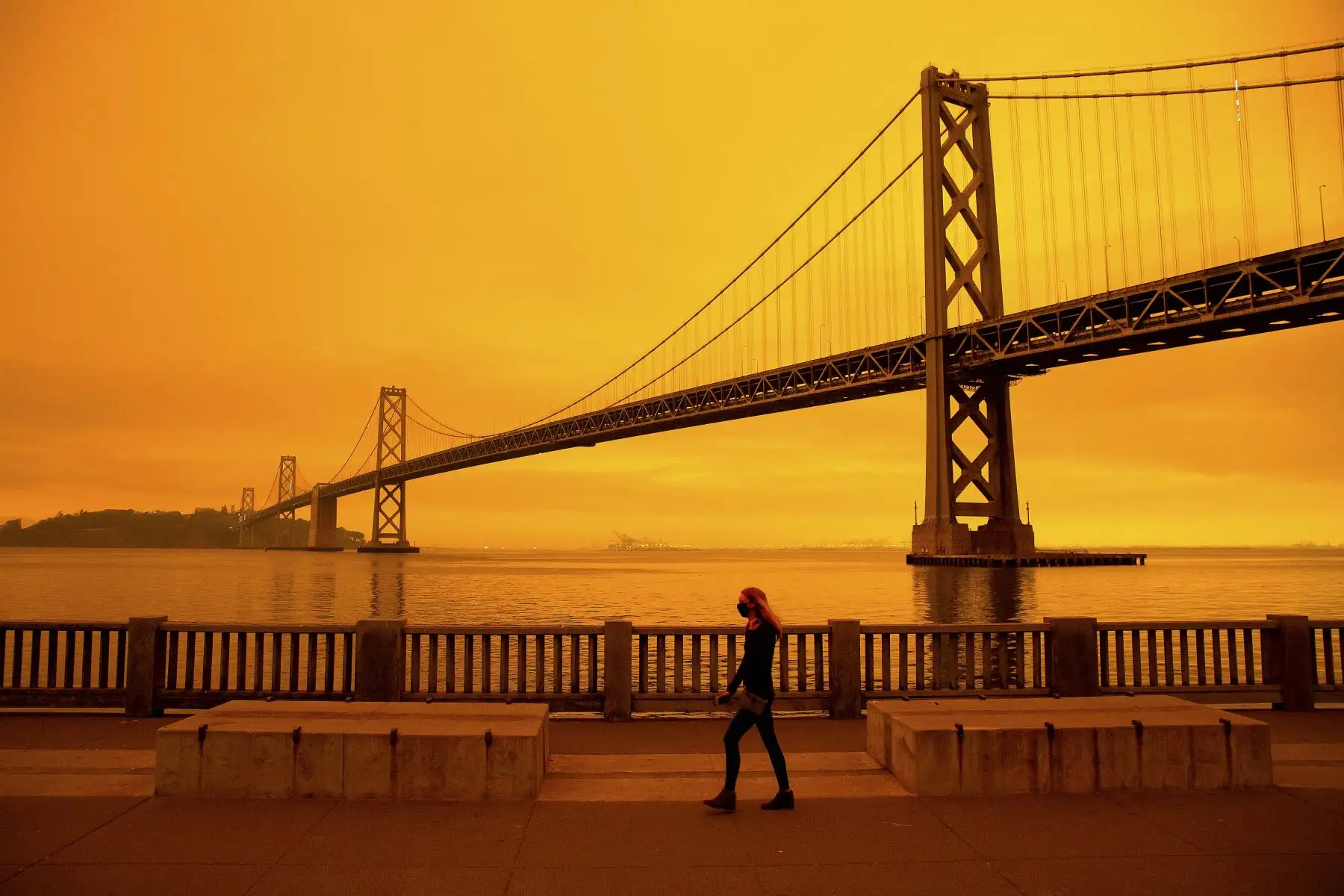 Una mujer camina por el Embarcadero bajo un cielo lleno de humo naranja en San Francisco, California. Más de 300,000 acres están ardiendo en todo el estado del noroeste, incluidos 35 incendios forestales importantes, con al menos cinco ciudades "sustancialmente destruidas". Foto: AFP
