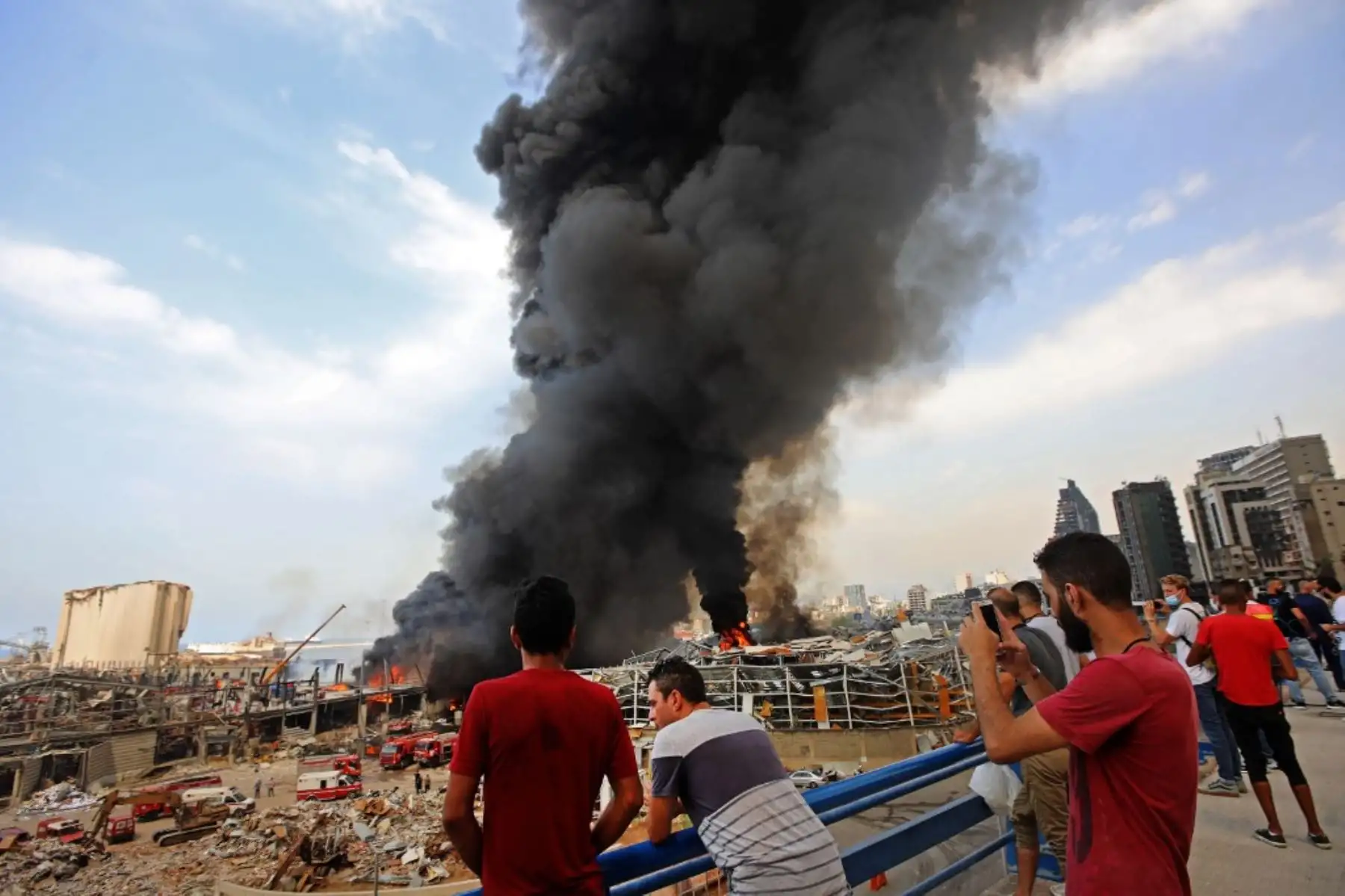 Los transeúntes observan como los bomberos libaneses intentan apagar un incendio en el área del puerto de Beirut. Foto:AFP