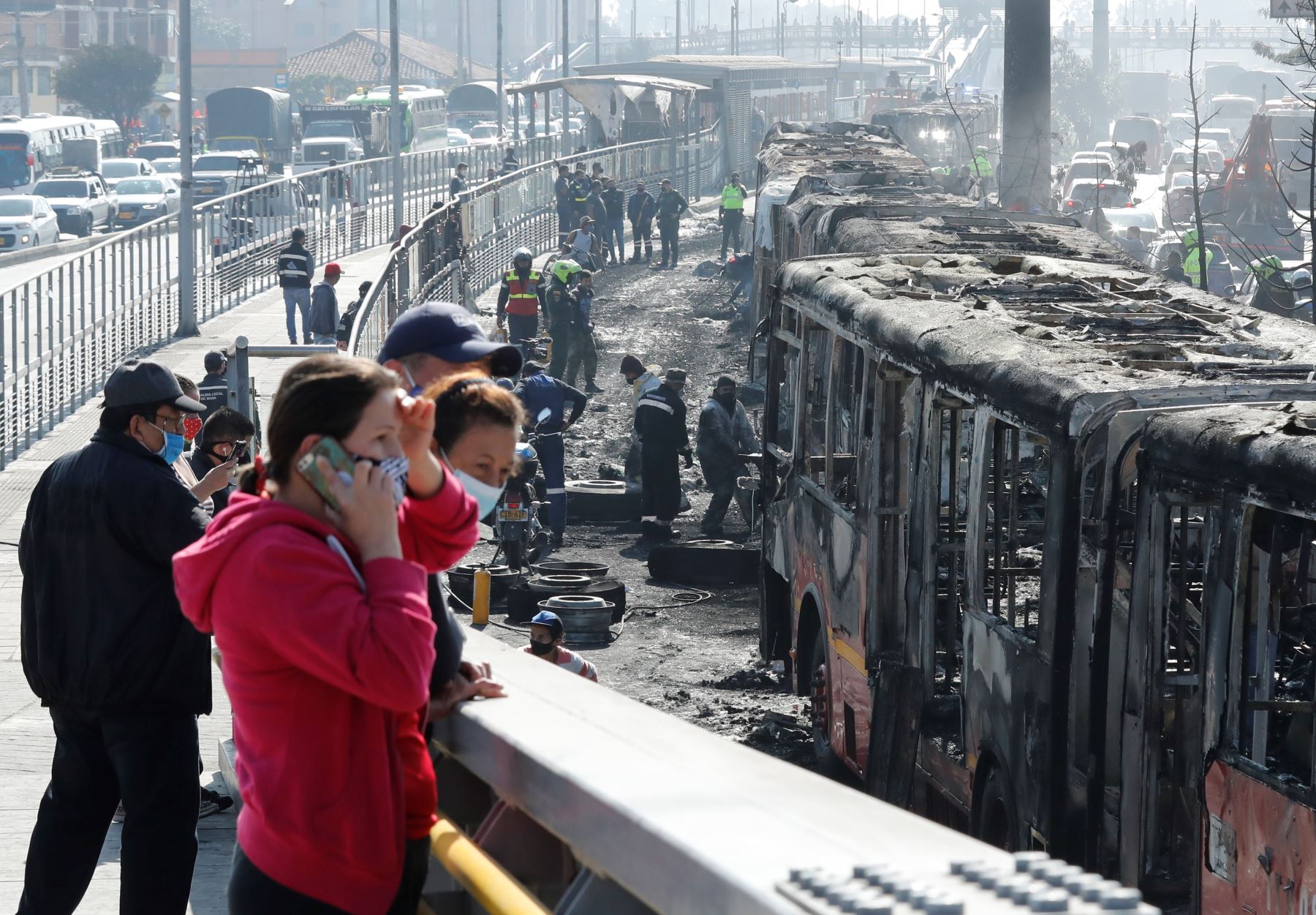 Ciudadanos observan hoy los restos incinerados de buses de TransMilenio en la localidad de Bosa, en Bogotá (Colombia). Foto: EFE