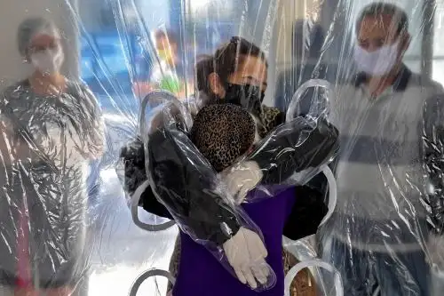 En esta fotografía de archivo tomada el 13 de junio de 2020, Elisabete Nagata abraza a su cuñada Luiza Nagata, de 76 años, a través de una cortina de plástico transparente en un hogar de ancianos en Sao Paulo, Brasil. en medio de la pandemia del nuevo coronavirus. Foto: AFP