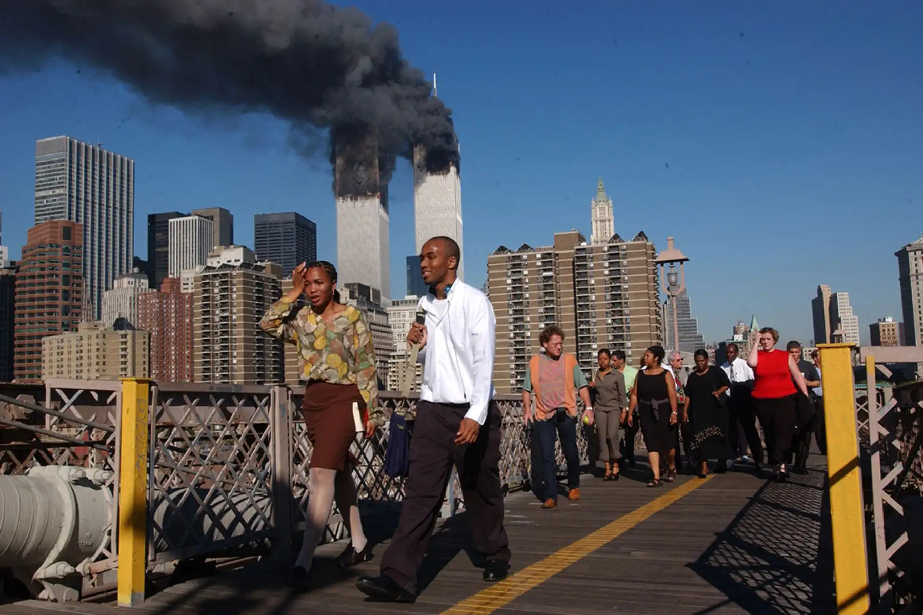 Decenas de personas caminan sobre el puente de Brooklyn mientras el World Trade Center arde el 11 de setiembre de 2001 después de que dos aviones secuestrados se estrellaran contra las Torres Gemelas en la ciudad de Nueva York. 
Foto: AFP