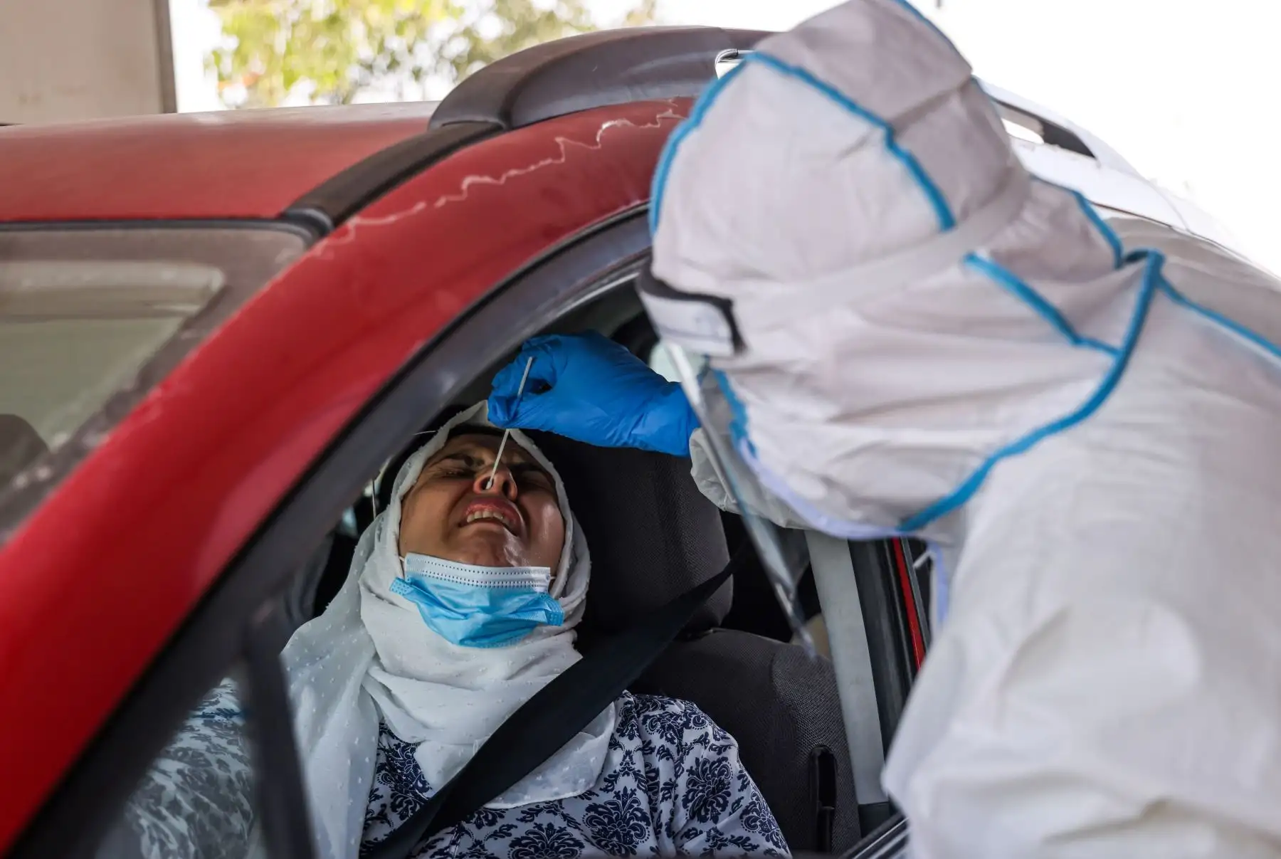 Un miembro del servicio médico de emergencia nacional Magen David Adom, a través de la ventana de un vehículo, realiza una prueba de muestra con hisopo para detectar la enfermedad por coronavirus. Foto: AFP