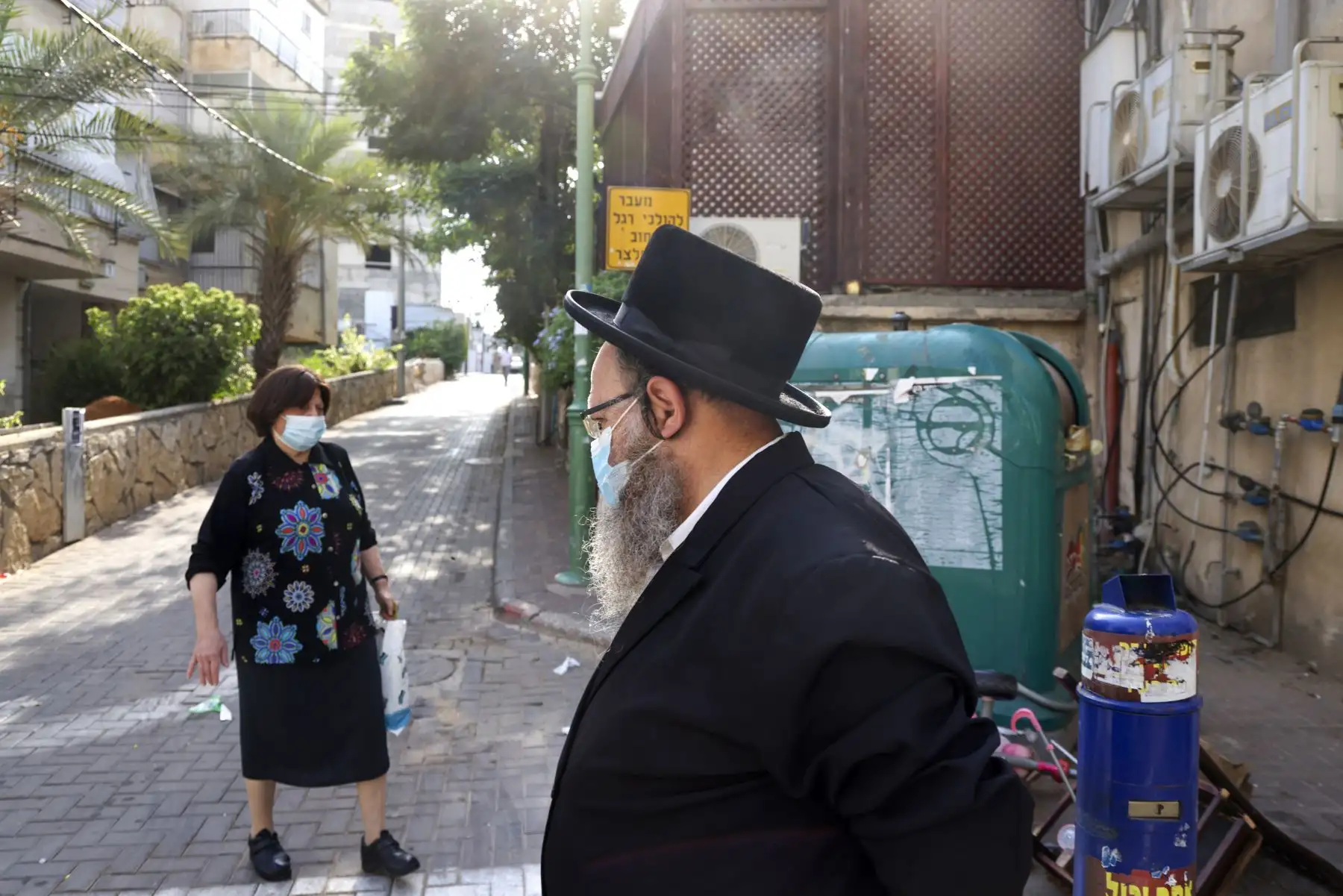Judíos ultraortodoxos, con una mascarilla protectora debido a la pandemia del coronavirus, caminan por una calle en la ciudad ultraortodoxa de Bnei Brak, cerca de Tel Aviv. Foto: AFP