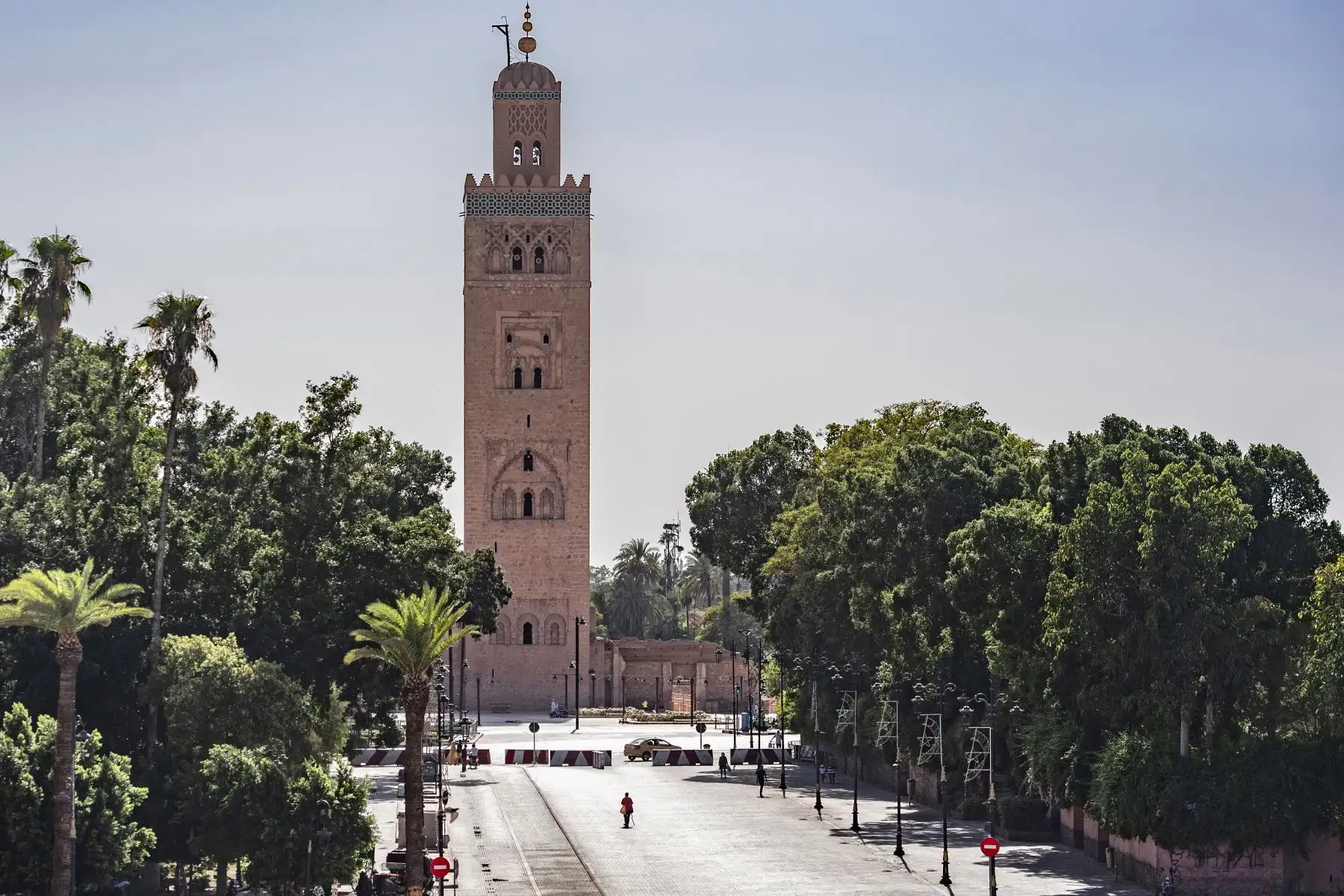 Algunas personas caminan junto a la torre del minarete de la mezquita Kutubiyya en la plaza Jemaa el-Fna en la ciudad de Marrakech, actualmente vacía de sus multitudes habituales debido a la pandemia por coronavirus. Foto: AFP