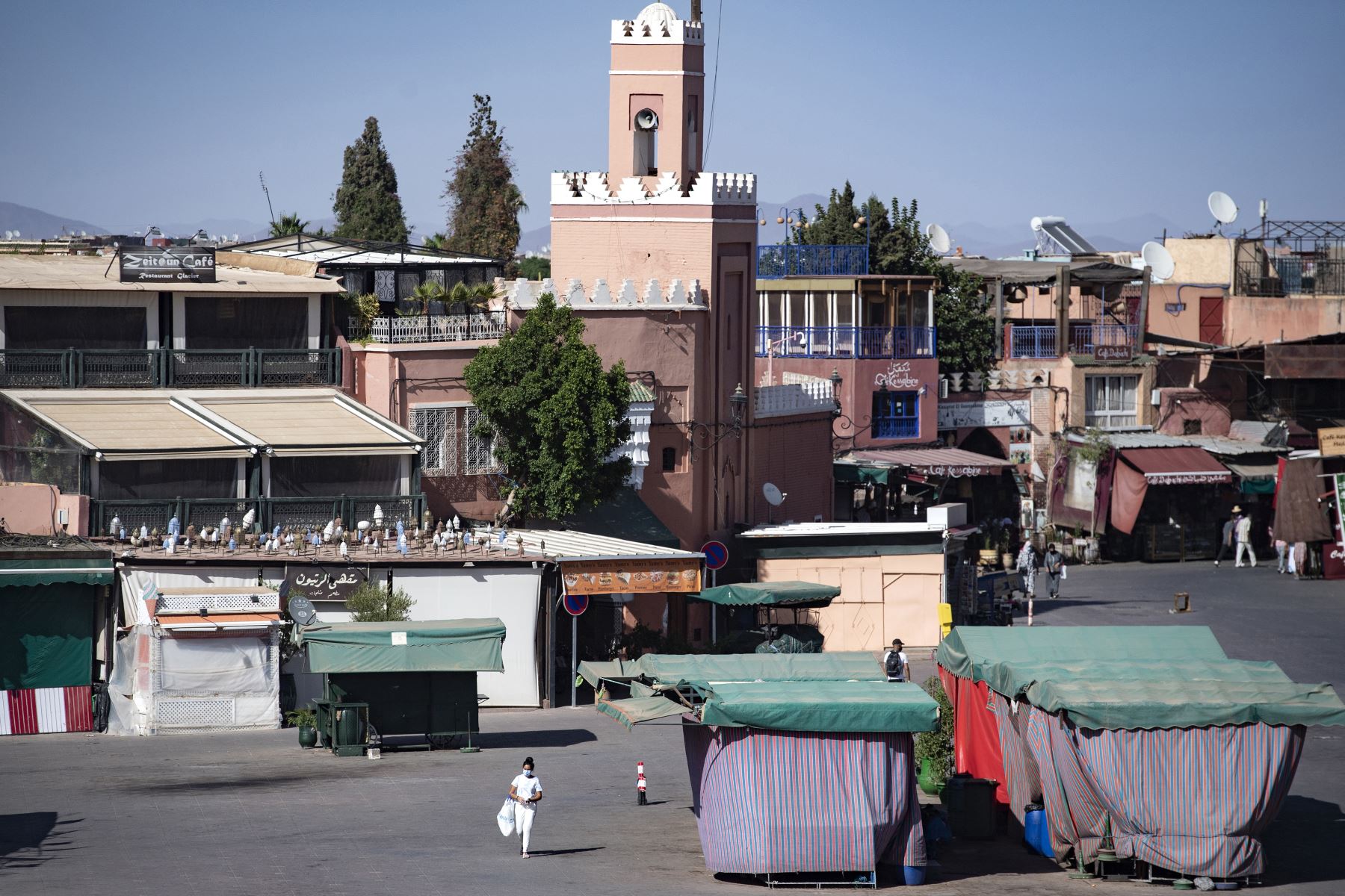 Algunas personas, con mascarillas, pasan por la plaza Jemaa el-Fna en la ciudad marroquí de Marrakech, actualmente vacía de sus multitudes habituales debido a la pandemia de Covid-19. Foto: AFP