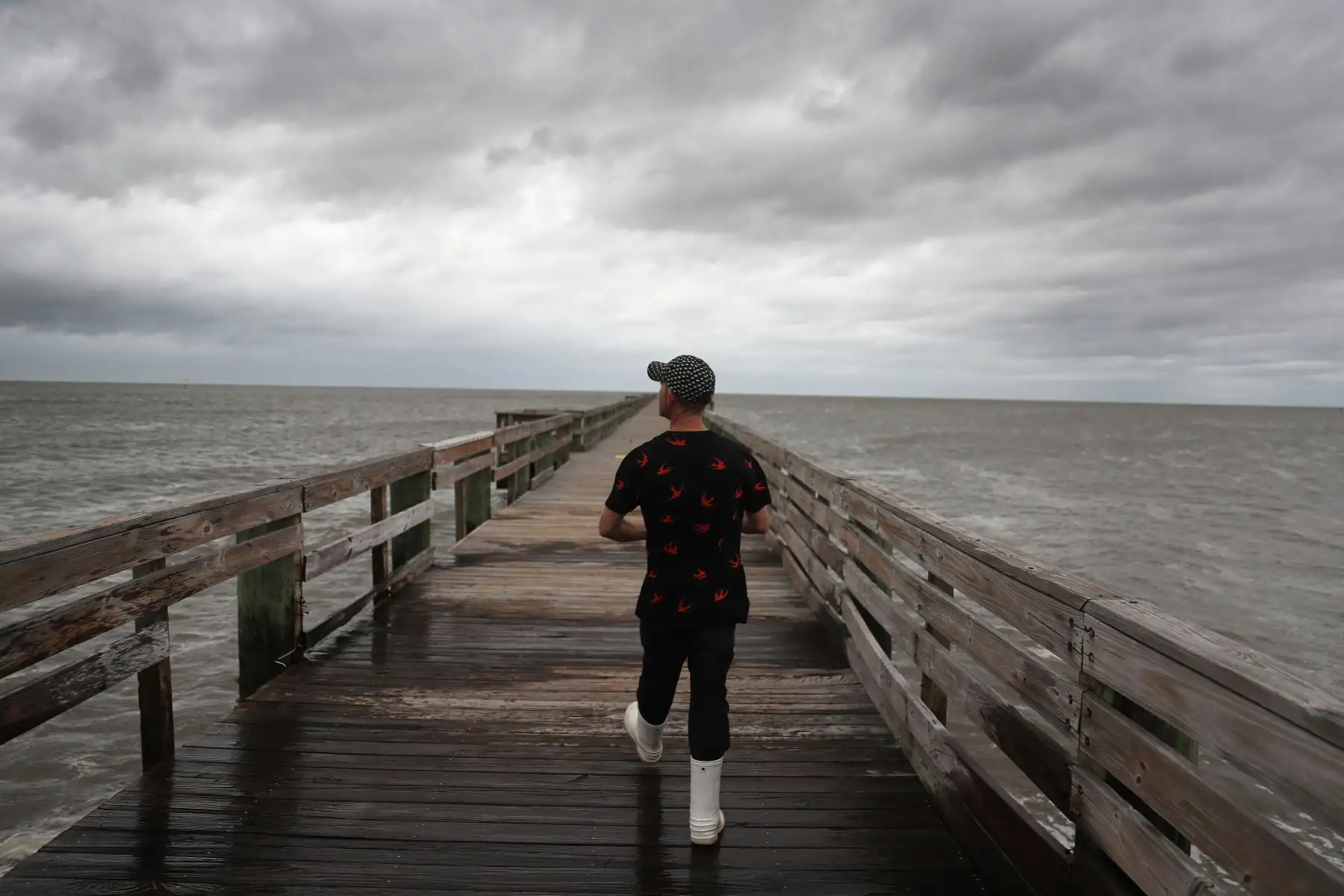 Un joven camina a lo largo de un muelle para encontrar un lugar para pescar antes de la posible llegada del huracán Sally, en Biloxi, Mississippi. Foto: AFP