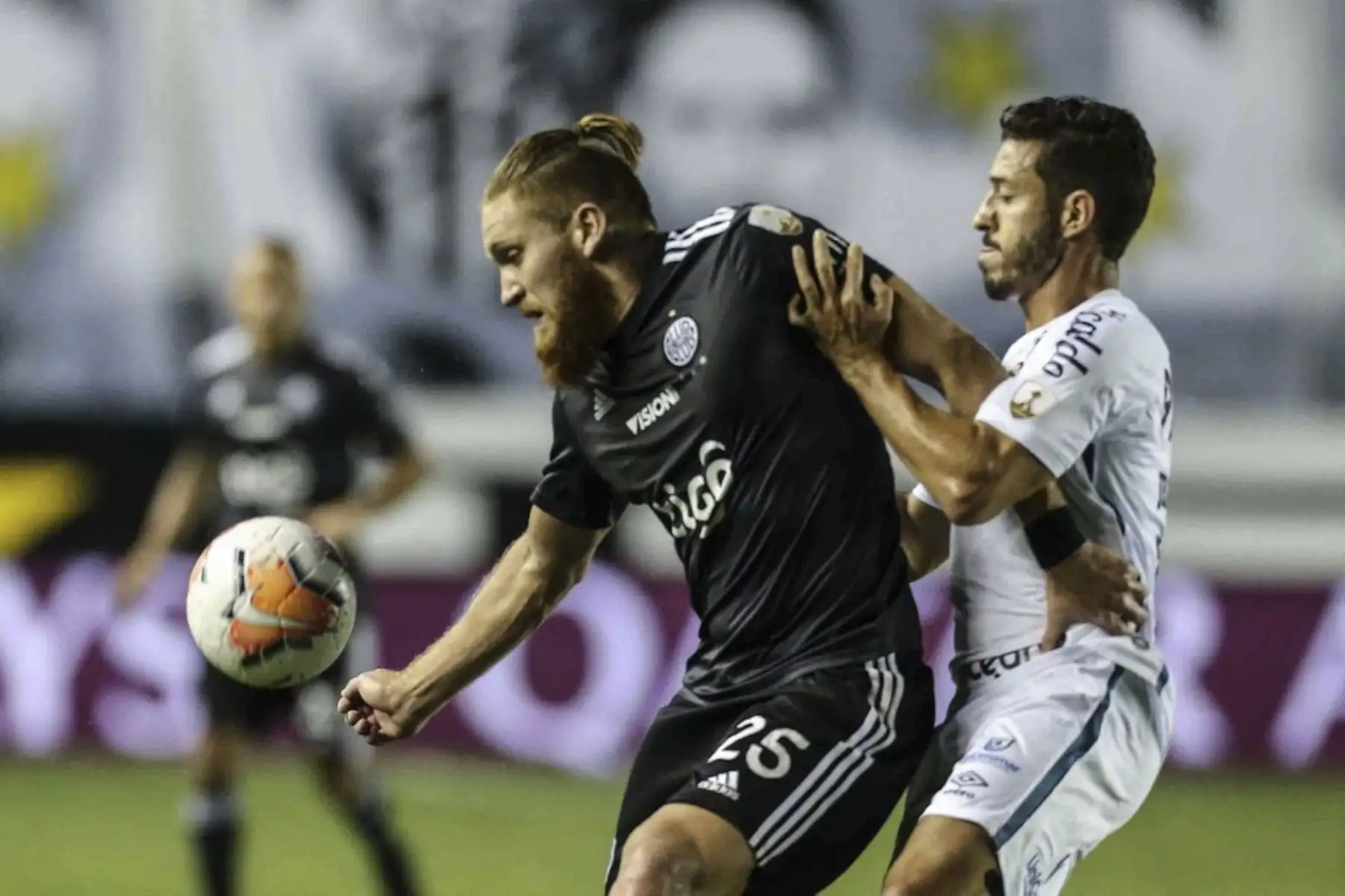 El mediocampista del Olimpia de Paraguay Isidro Pitta y  el mediocampista del Santos de Brasil, Jean Mota, compiten por el balón durante el partido a puertas cerradas por la fase de grupos de la Copa Libertadores en el estadio Vila Belmiro en Santos, Brasil. Foto: AFP