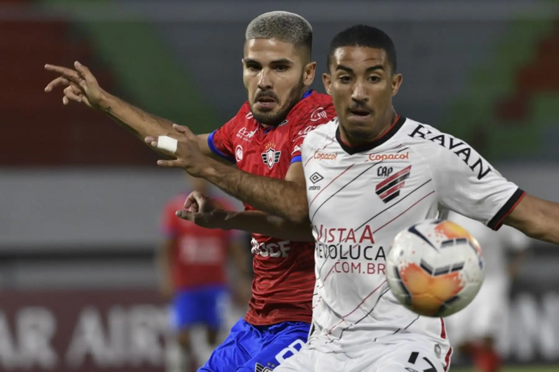 El centrocampista del Club Deportivo Jorge Wilstermann de Bolivia, Carlos Melgar, y el mediocampista del Atlético Paranaense de Brasil, Christian Alves, compiten por el balón durante el partido de fútbol a puertas cerradas por la fase de grupos de la Copa Libertadores en el estadio Félix Capriles en Cochabamba, Bolivia. Foto: AFP