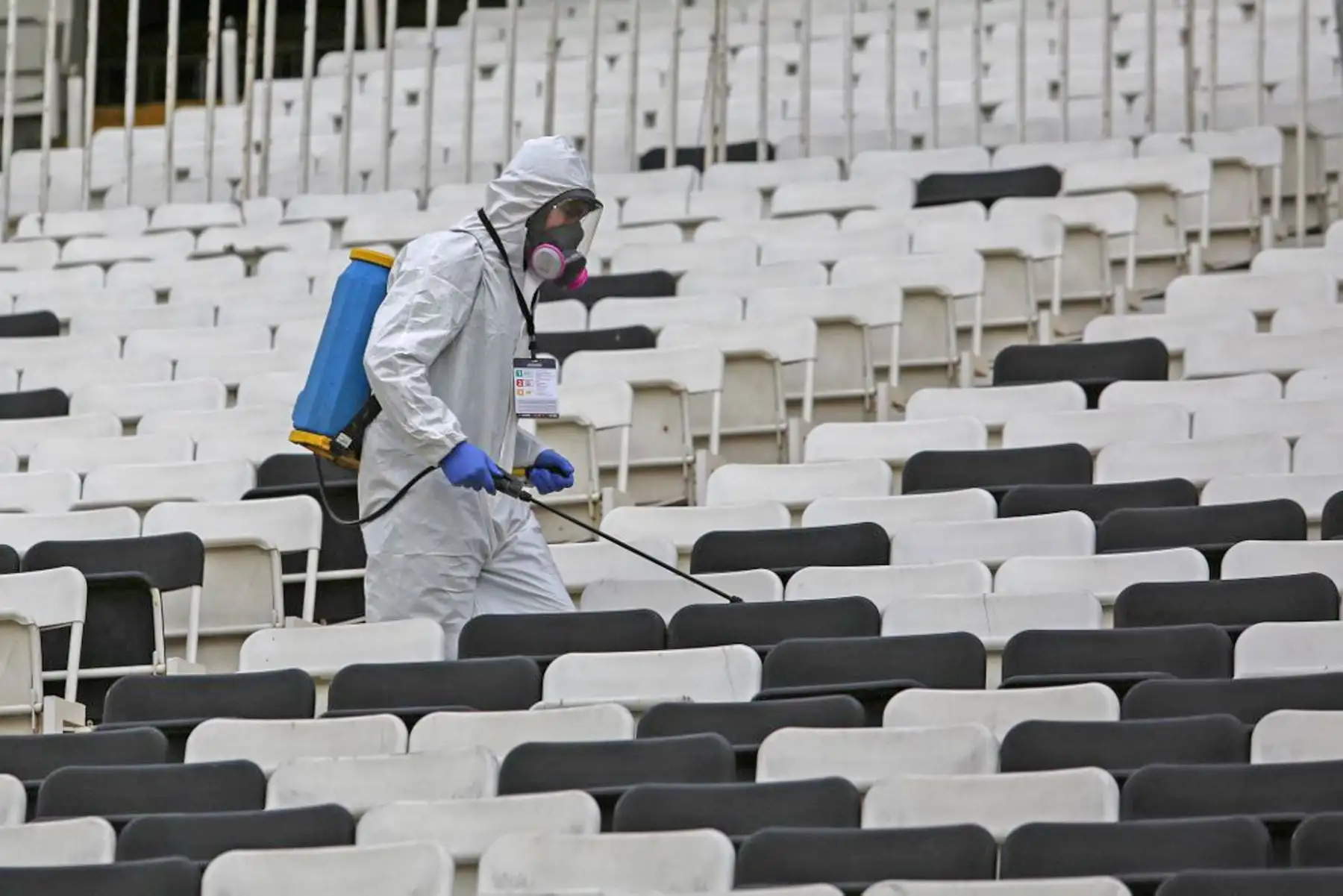Un trabajador desinfecta los asientos antes del inicio del partido de fútbol a puerta cerrada de la fase de grupos de la Copa Libertadores entre Colo Colo de Chile y Peñarol de Uruguay, en el estadio Monumental de Santiago. Foto: AFP