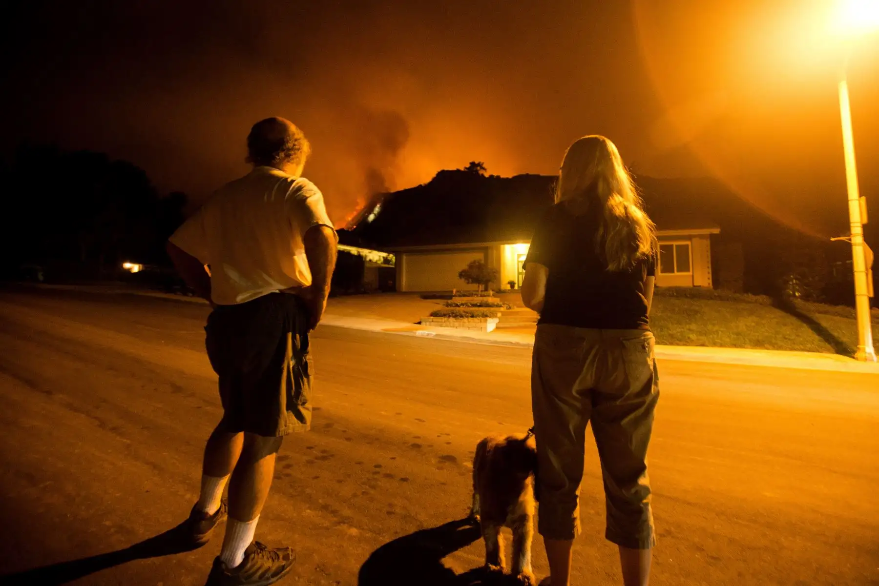 Las personas observan cómo arden las llamas en las laderas detrás de sus viviendas en Monrovia, California. Foto: AFP