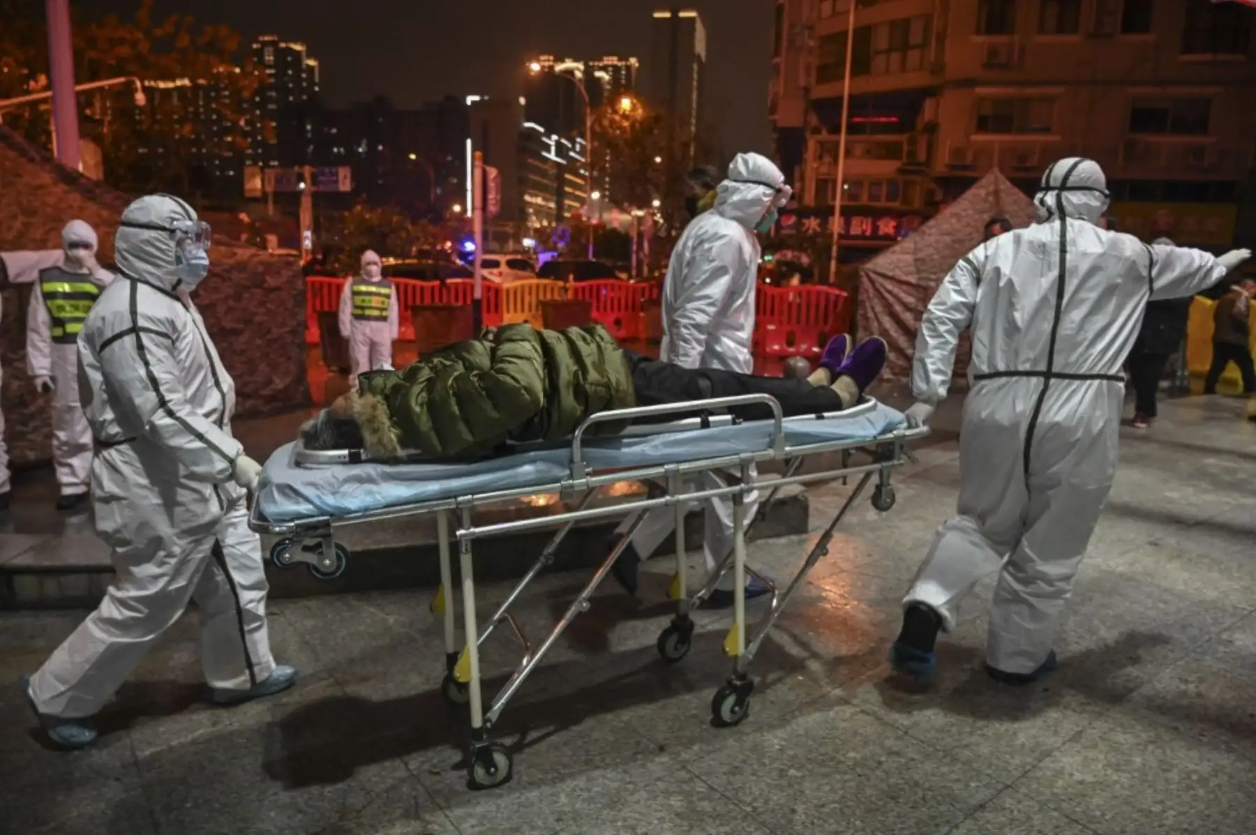 Miembros del personal médico con ropa protectora ayudan a un paciente  con covid-19 y lo  trasladan al Hospital de la Cruz Roja de Wuhan para detener la propagación del coronavirus.Foto:AFP