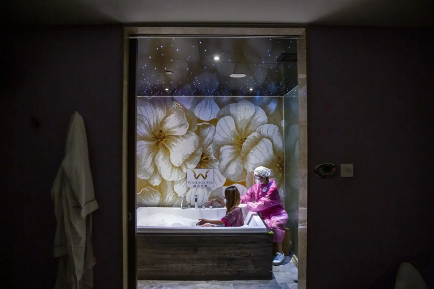 Un empleado que usa una máscara, protector facial y bata le da a un cliente un masaje en un spa en una casa de baños en Hong Kong, donde abrieron bares, piscinas y parques de diversiones, con restricciones después de los cierres debido a la tercera ola del coronavirus covid-19. Foto:AFP