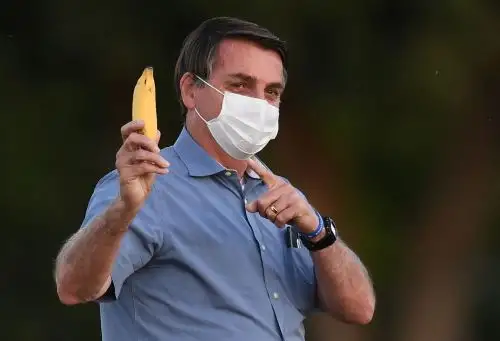 El presidente brasileño, Jair Bolsonaro, muestra una banana a los periodistas mientras camina hacia sus seguidores en el jardín del Palacio de la Alvorada en Brasilia, el 24 de julio de 2020. Foto: AFP