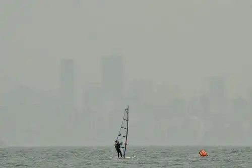 Un windsurfista navega en la ensenada de Burrard en Vancouver, Canadá mientras el denso smog y el olor a humo de madera se ciernen sobre el horizonte. El humo de los incendios forestales de California y Oregon ha cubierto Vancouver, conocida por sus majestuosas vistas a las montañas y brisas frescas del océano, en el aire más sucio del mundo esta semana. Foto: AFP