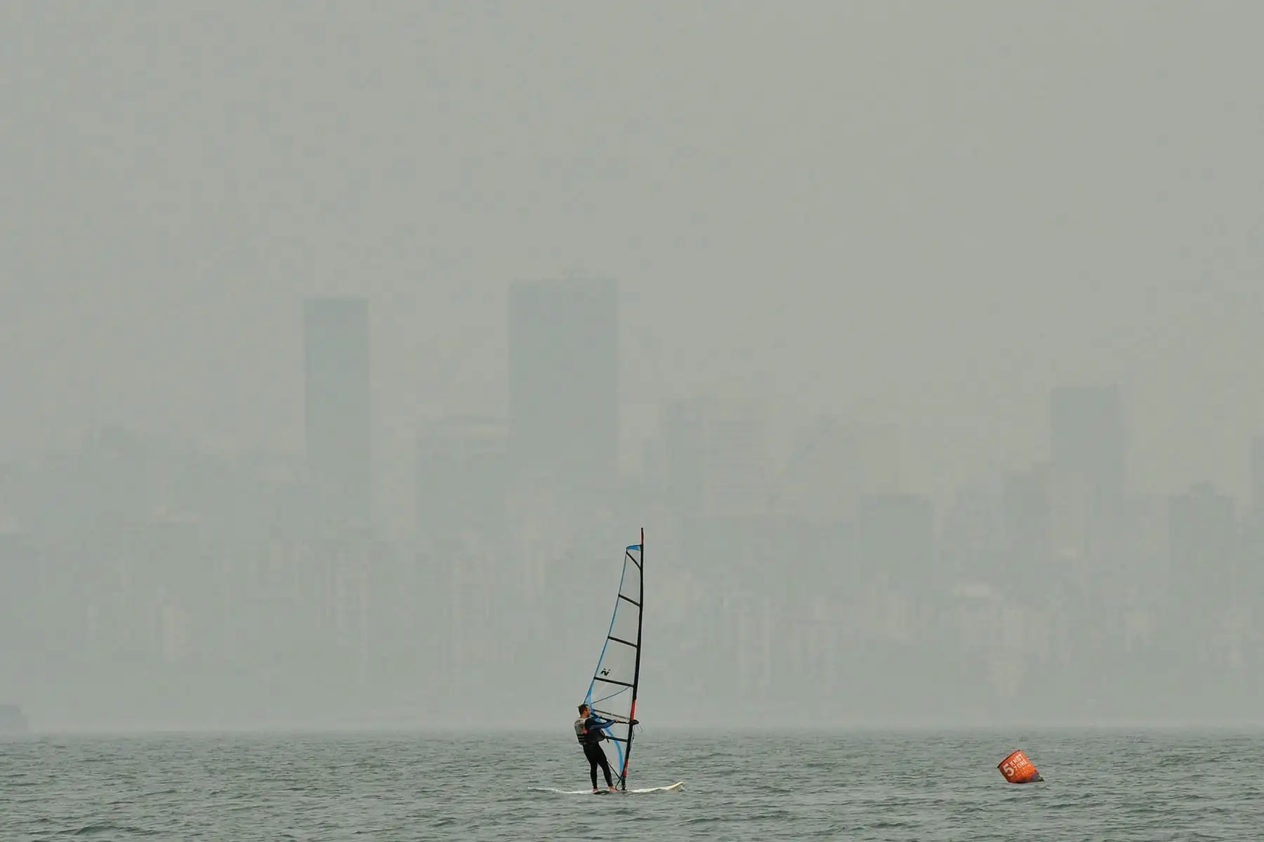 Un windsurfista navega en la ensenada de Burrard en Vancouver, Canadá mientras el denso smog y el olor a humo de madera se ciernen sobre el horizonte. El humo de los incendios forestales de California y Oregon ha cubierto Vancouver, conocida por sus majestuosas vistas a las montañas y brisas frescas del océano, en el aire más sucio del mundo esta semana. Foto: AFP