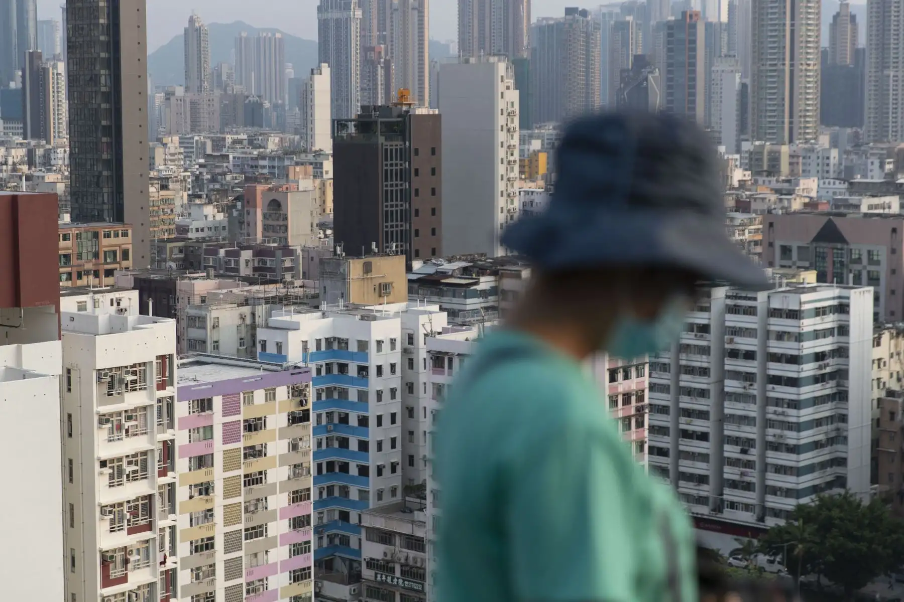 Una mujer usa una mascarilla como medida de precaución ante el coronavirus pasa frente a edificios de viviendas, en Hong Kong. Foto: AFP