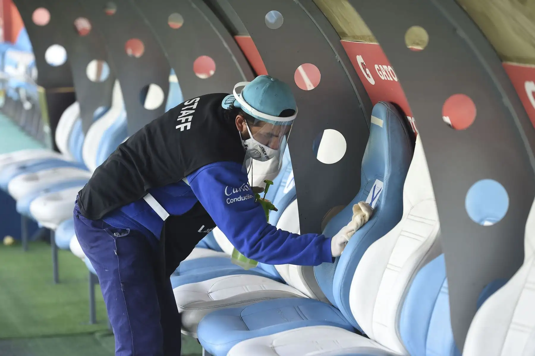 Un trabajador desinfecta el banco de suplentes antes del inicio de un partido de fútbol a puertas cerradas por la fase de grupos de la Copa Libertadores, entre el Racing de Argentina y el Nacional de Uruguay, en el Estadio Presidente Perón de Buenos Aires. Foto: AFP