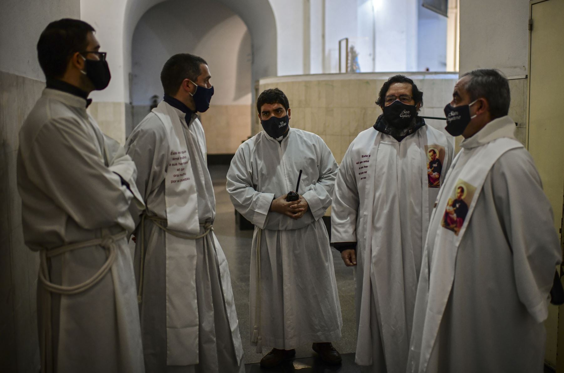 Los sacerdotes, cubiertos con mascarillas, dialogan antes de una misa dentro de la iglesia cerrada de San Cayetano, en Buenos Aires. Foto: AFP