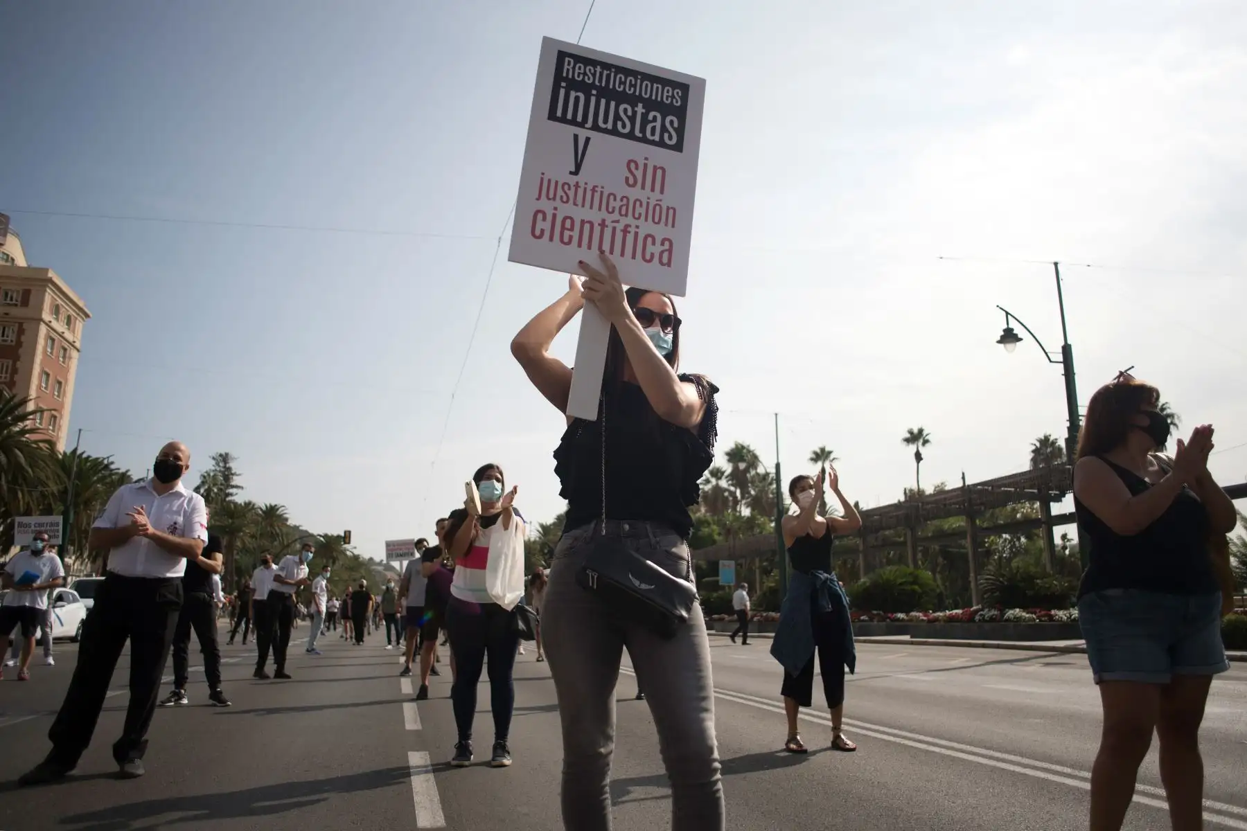 Personas sostienen pancartas durante una protesta contra las restricciones impuestas a bares, restaurantes y discotecas para luchar contra la propagación del Covid-19, en Málaga, España. Foto: AFP