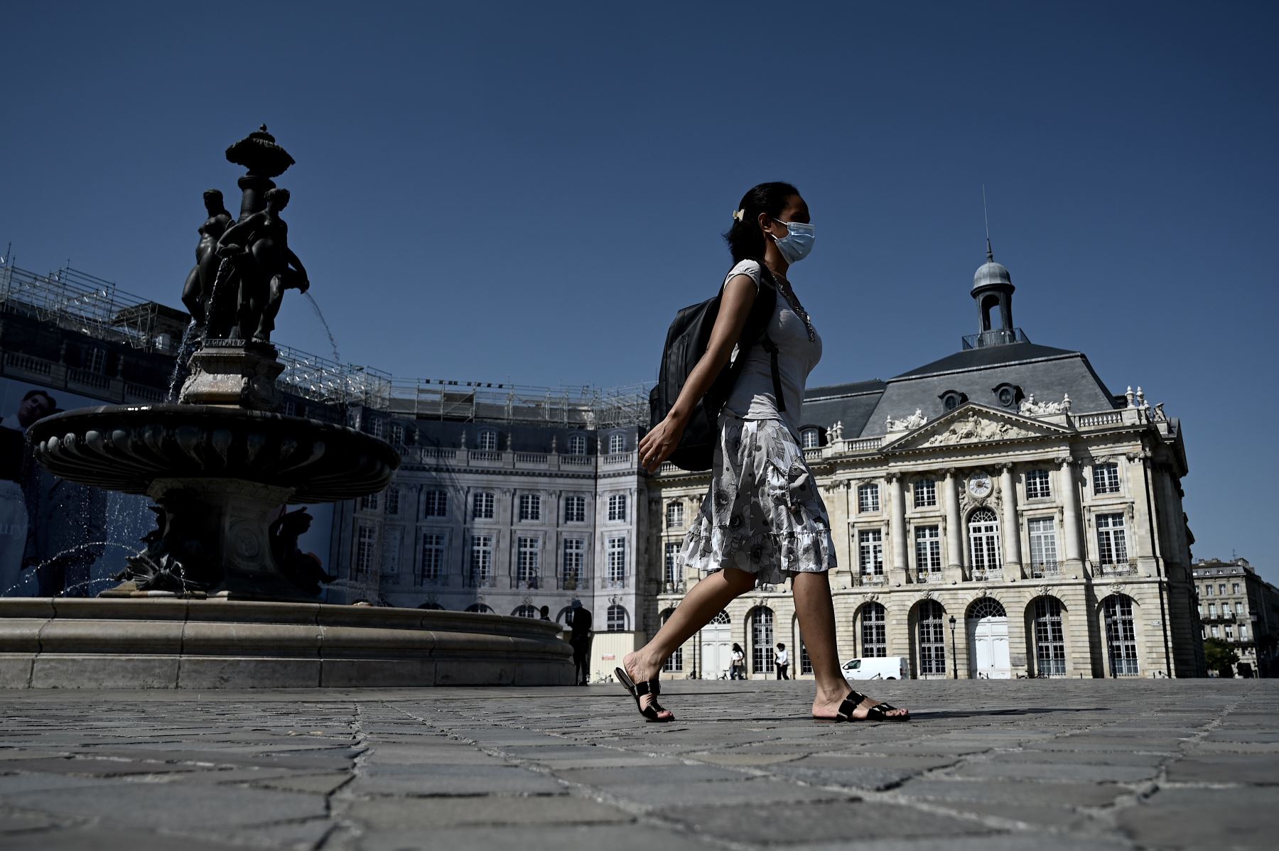 Una mujer con una máscara protectora transita por la Place de la Bourse, en Burdeos, suroeste de Francia. Foto: AFP