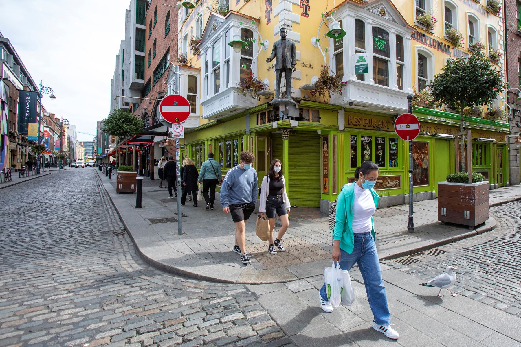 Los peatones usan máscara facial mientras transitan por los pubs cerrados temporalmente para controlar la transmisión por coronavirus, en Dublín, Irlandia. Foto: AFP