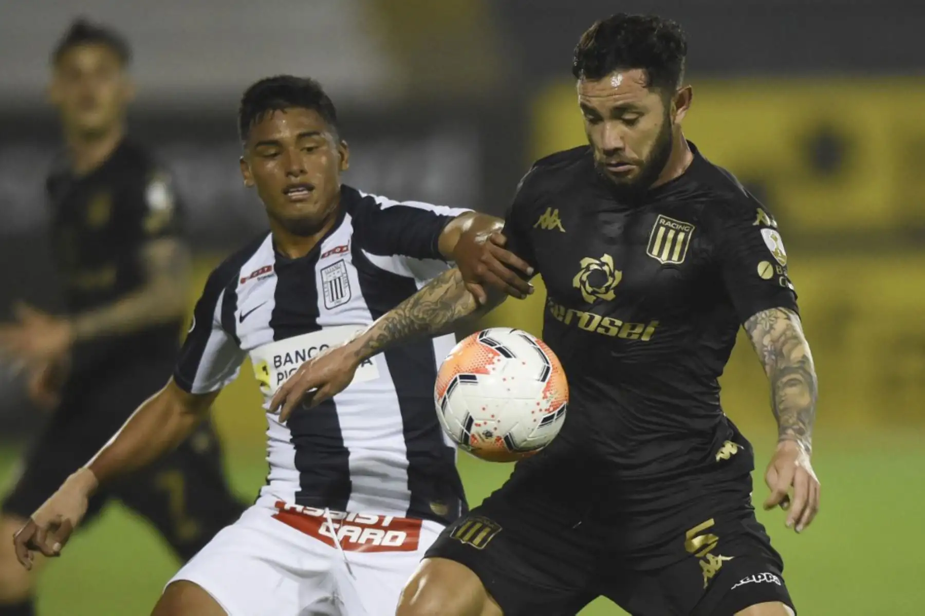 El defensor peruano de Alianza Lima Kluiverth Aguilar  y el defensor del Racing Club de Argentina, el chileno Eugenio Mena compiten por el balón durante su partido de fútbol a puerta cerrada de la fase de grupos de la Copa Libertadores en el Estadio Alejandro Villanueva en Lima. Foto: AFP