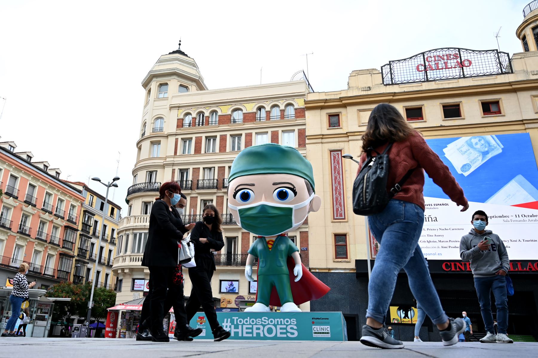 Personas con mascarillas alrededor a una estatua de seis metros de altura con referencia a un "súper trabajador de la salud" instalado en Madrid, para rendir homenaje a los médicos que luchan contra el coronavirus. Foto: AFP