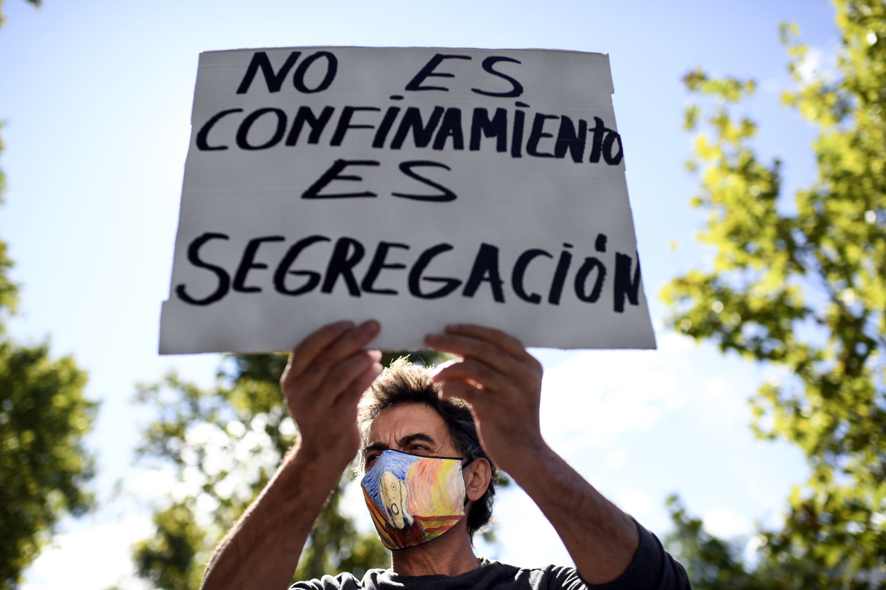 Un manifestante sostiene un cartel durante una manifestación en contra de las restricciones impuestas por el gobierno regional para combatir la propagación del coronavirus, en el distrito de Vallecas, en Madrid. Foto: AFP