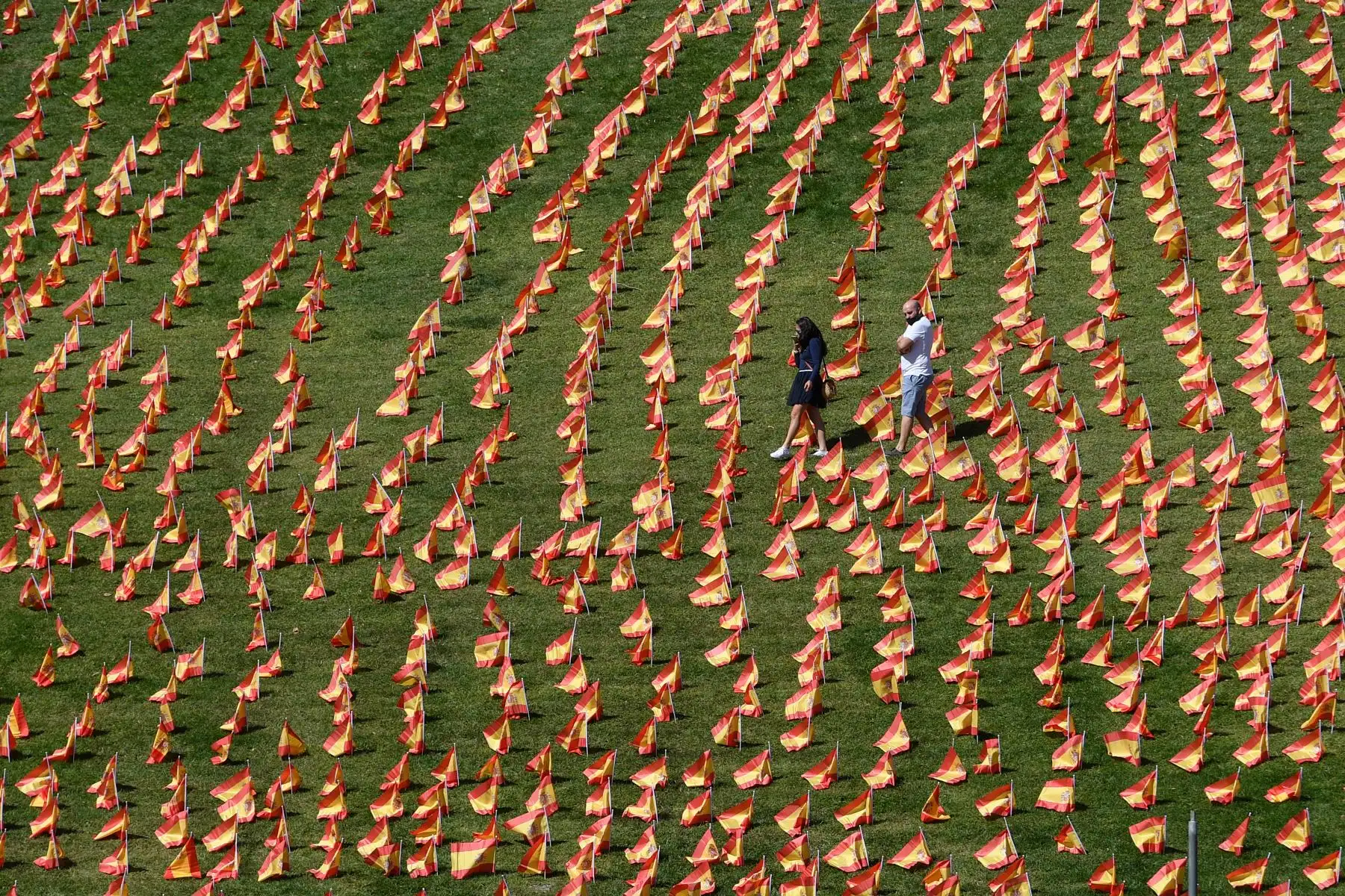 Una pareja camina entre miles de banderas españolas, que representan a las víctimas  Covid-19, en el parque de Roma, en Madrid. Foto: AFP