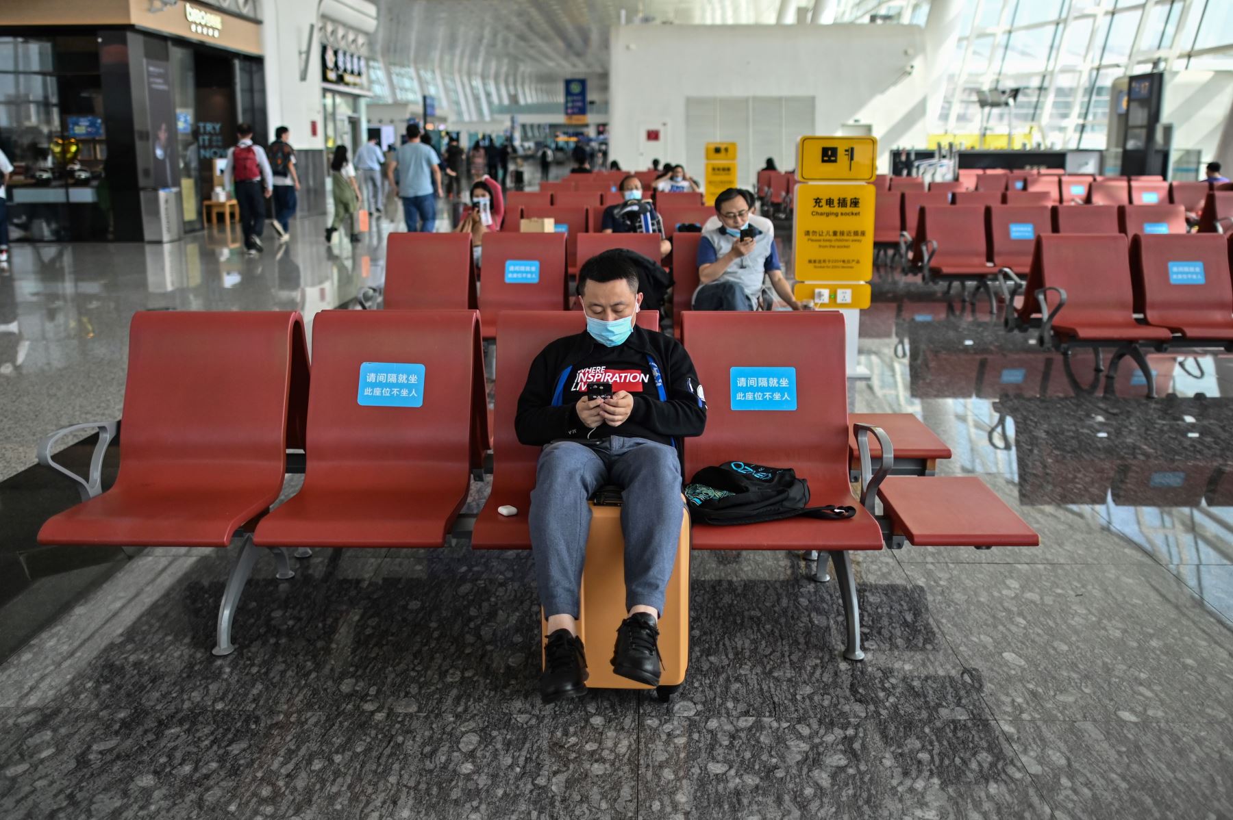 Personas que usan mascarillas como medida preventiva contra el coronavirus esperan sus vuelos en el aeropuerto de Tianhe, en Wuhan, China. Foto: AFP