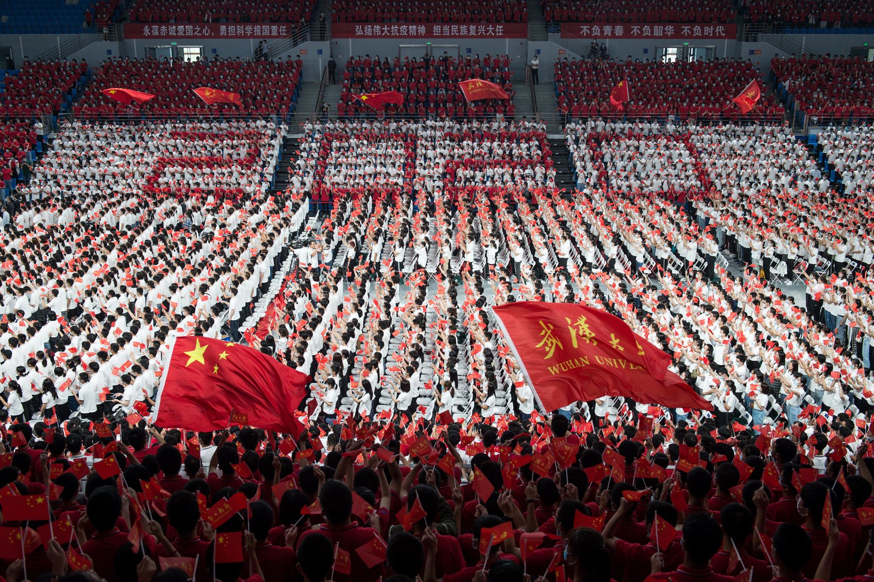 Estudiantes de primer año ondeando banderas chinas durante una ceremonia de graduación en la Universidad de Wuhan. Foto: AFP