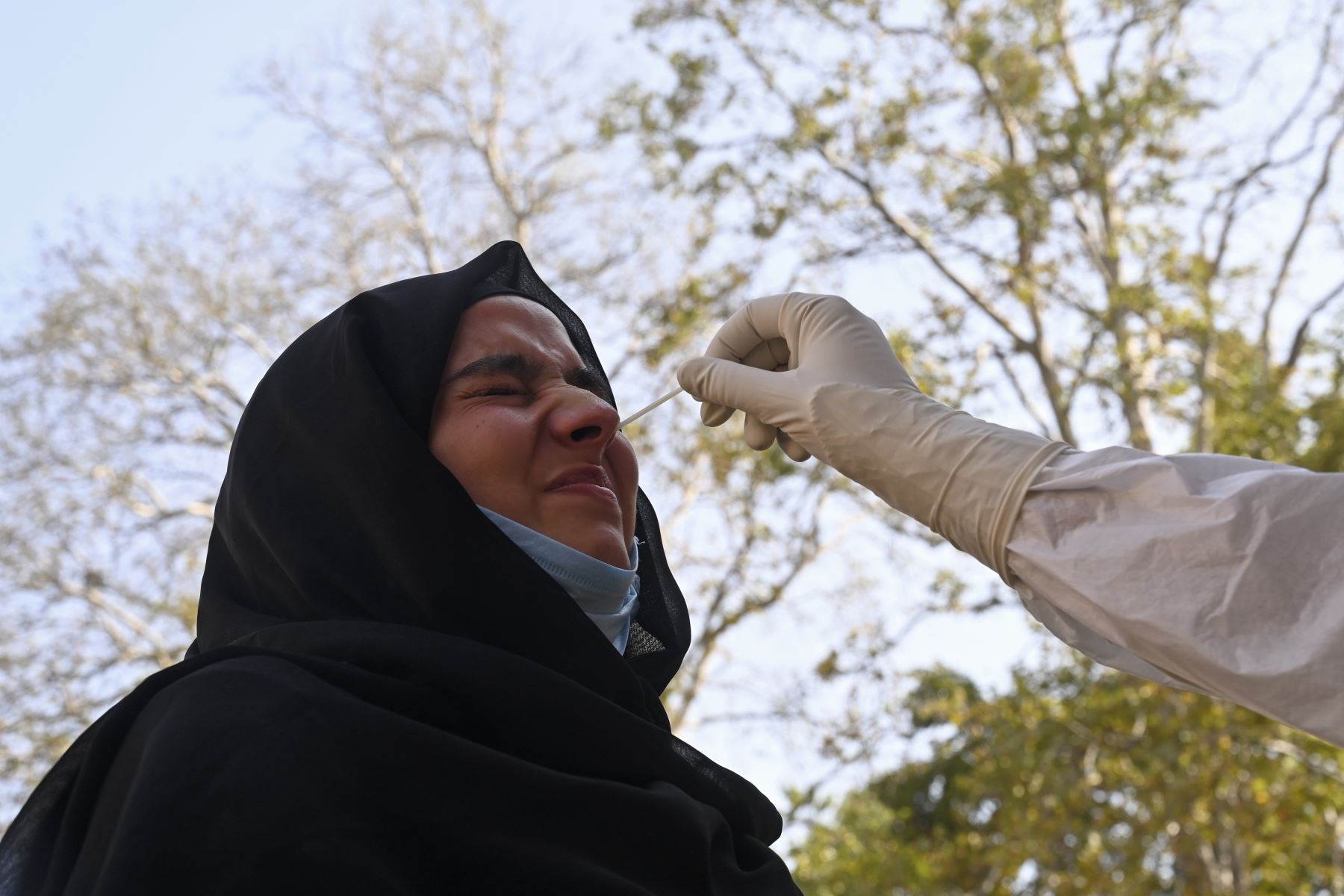 Una mujer reacciona cuando un trabajador médico recolecta una muestra de hisopo para una prueba rápida de antígeno para el coronavirus, en Srinagar. Foto: AFP
