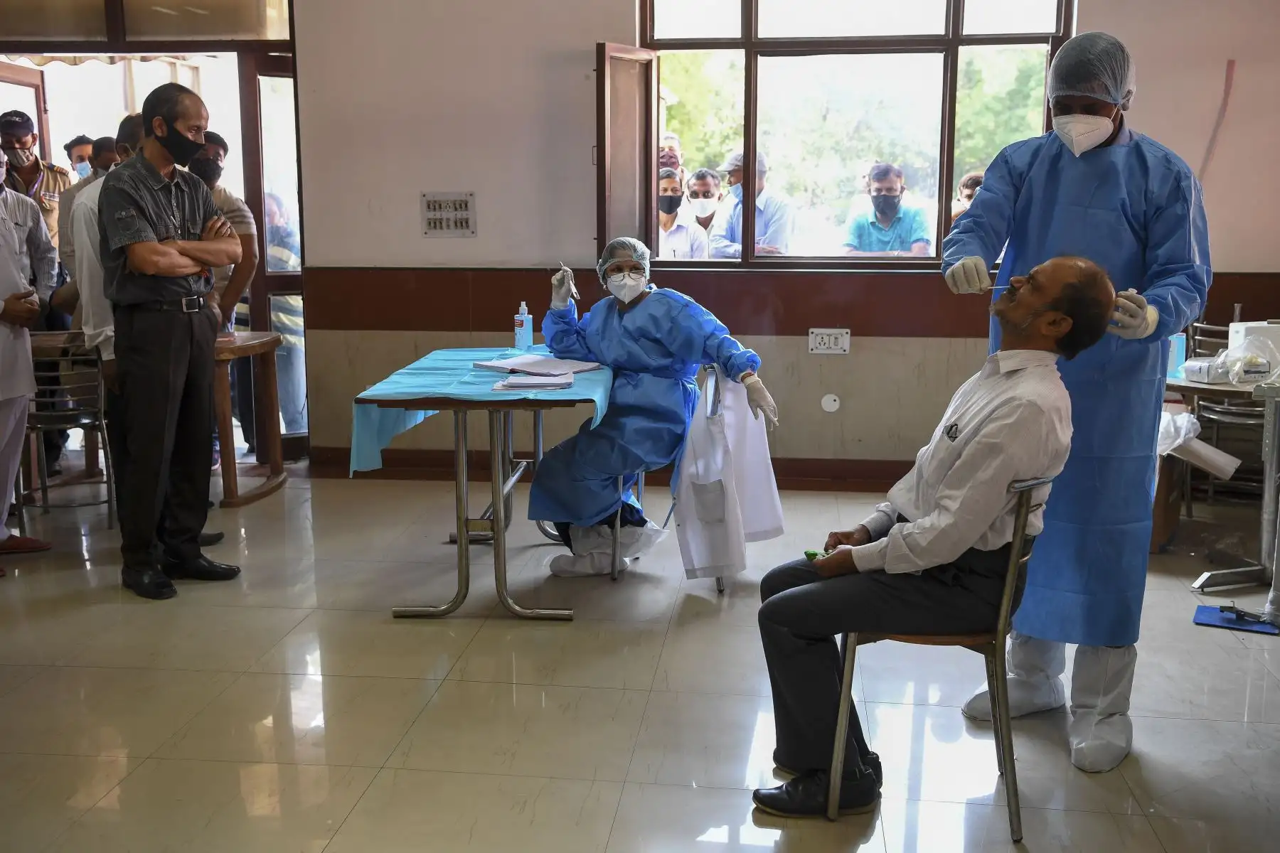 Un trabajador médico realiza pruebas de hisopo de un empleado del Instituto de Investigación Agrícola de la India (IARI), en Nueva Delhi. Foto: AFP
